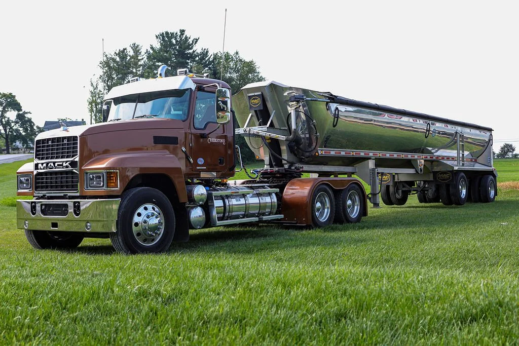 “Creekstone hauling truck with a brown and chrome cab parked on a grassy field, attached to a shiny stainless steel trailer, highlighting classic heavy-duty trucking and hauling capabilities.”
