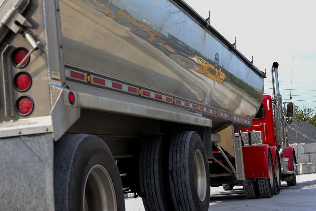 “Creekstone red truck with a reflective silver water tank parked on a construction site with concrete blocks and gravel in the background, highlighting emergency vehicle support and site safety operations.”