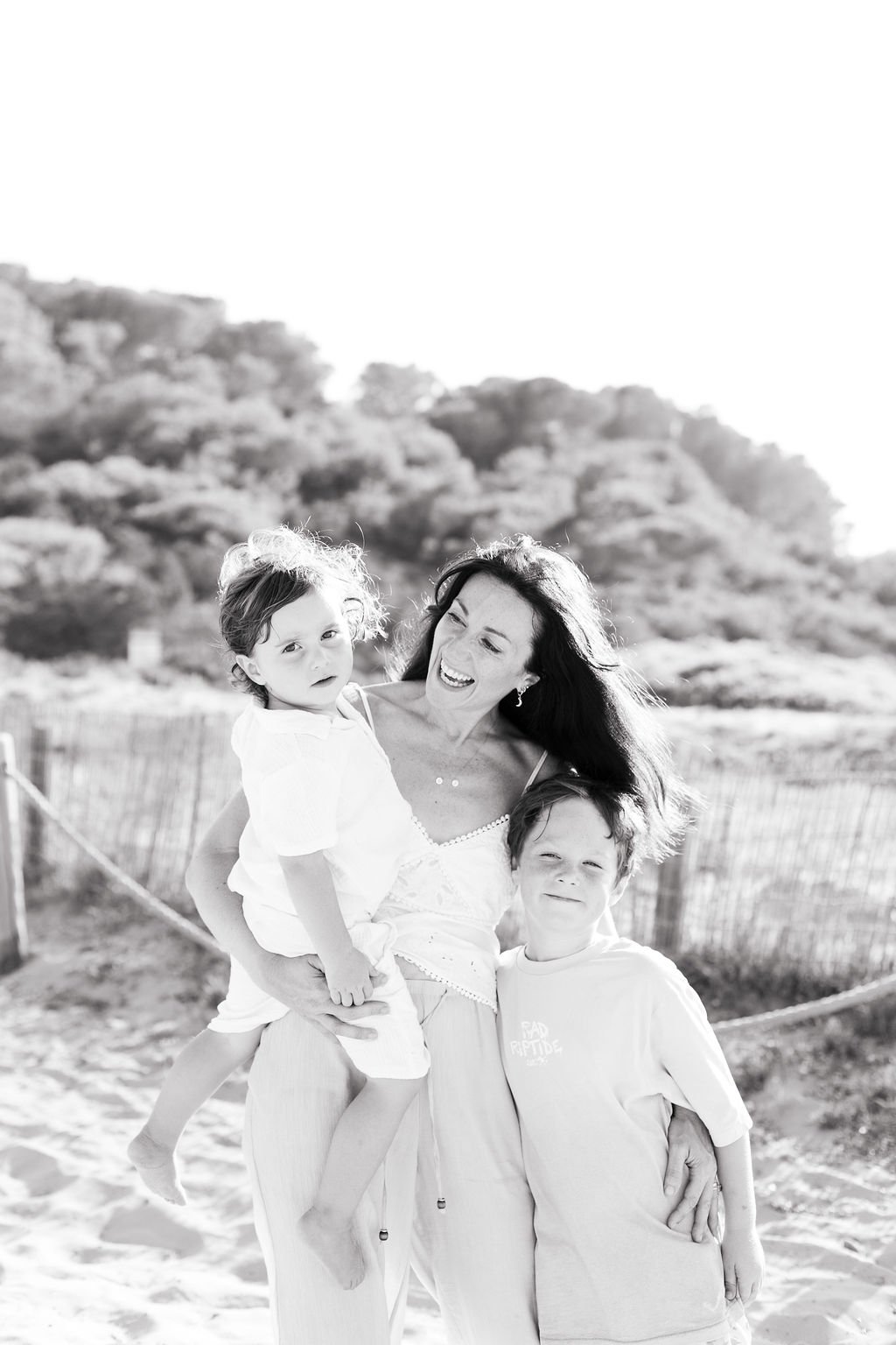A happy mother experiencing Matrescence with her children on a beach
