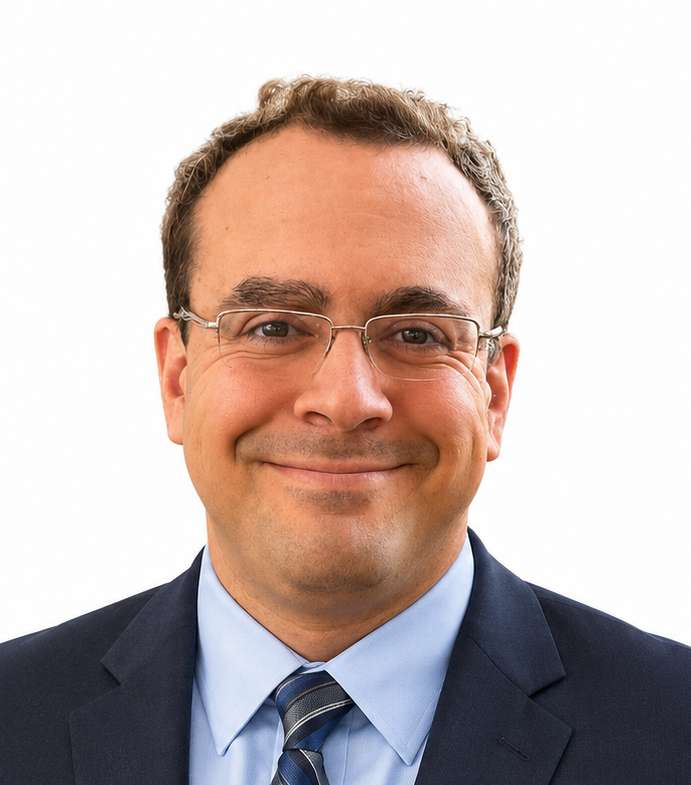 Portrait of a man wearing glasses and a blue button-up shirt, smiling against a plain white background.