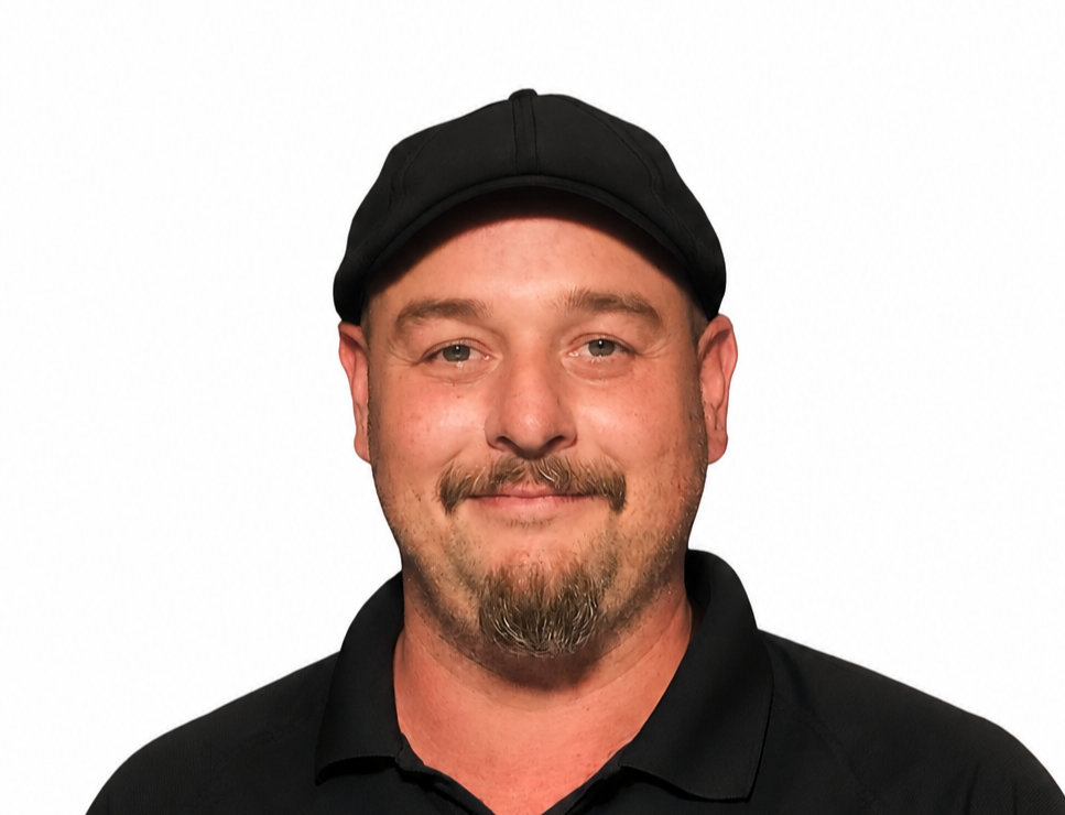 A man wearing a gray cap and light blue collared shirt, smiling against a plain white background.