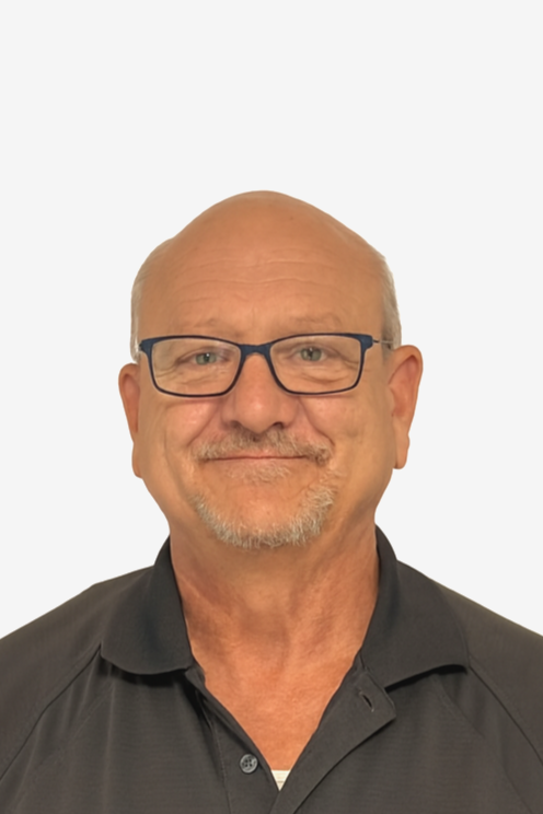 A middle-aged man with glasses, a short beard, and a mustache, smiling, wearing a black collared shirt against a plain white background.