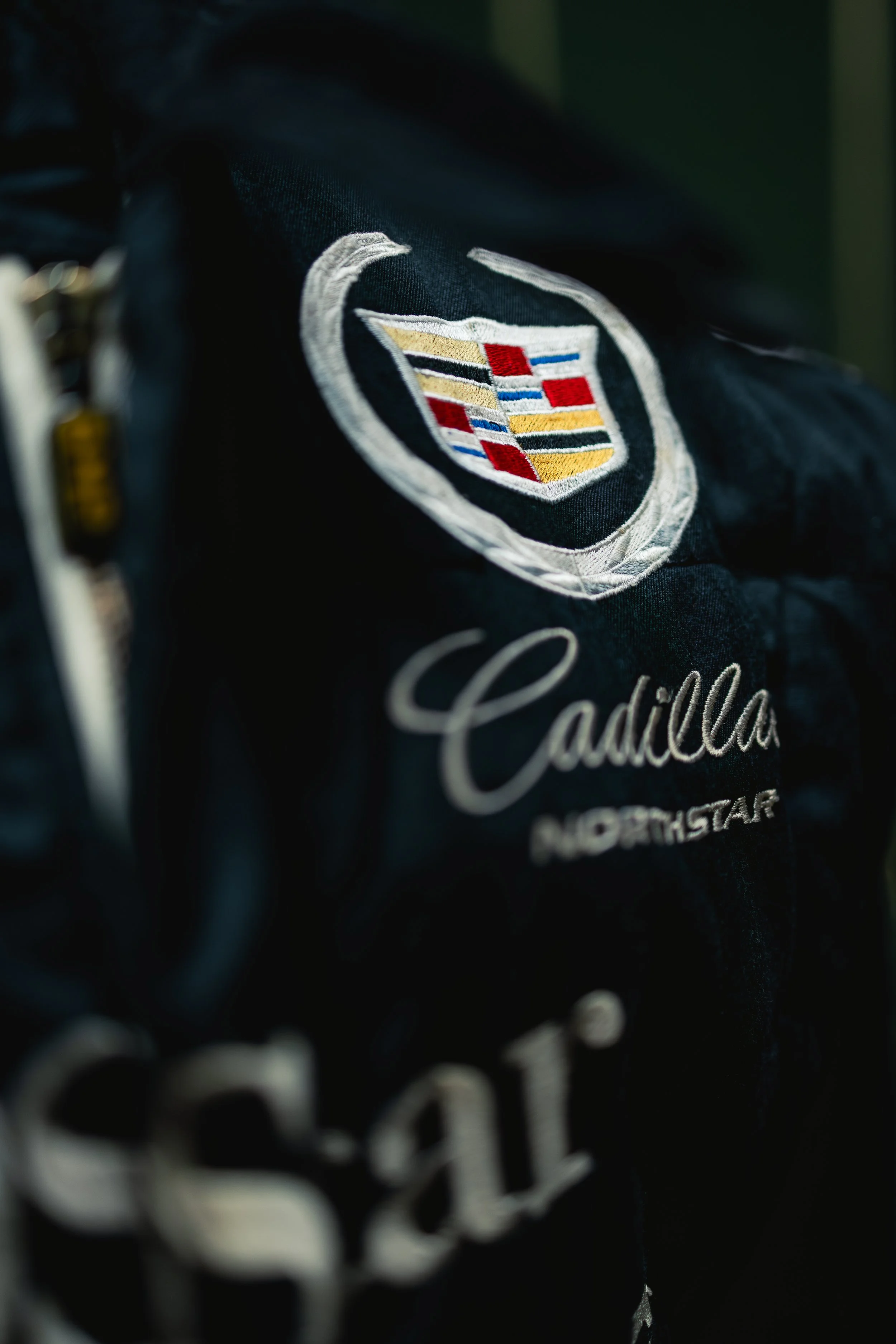 Close-up of a black racing jacket with Cadillac logo and embroidered text 'Cadillac Northstar'.