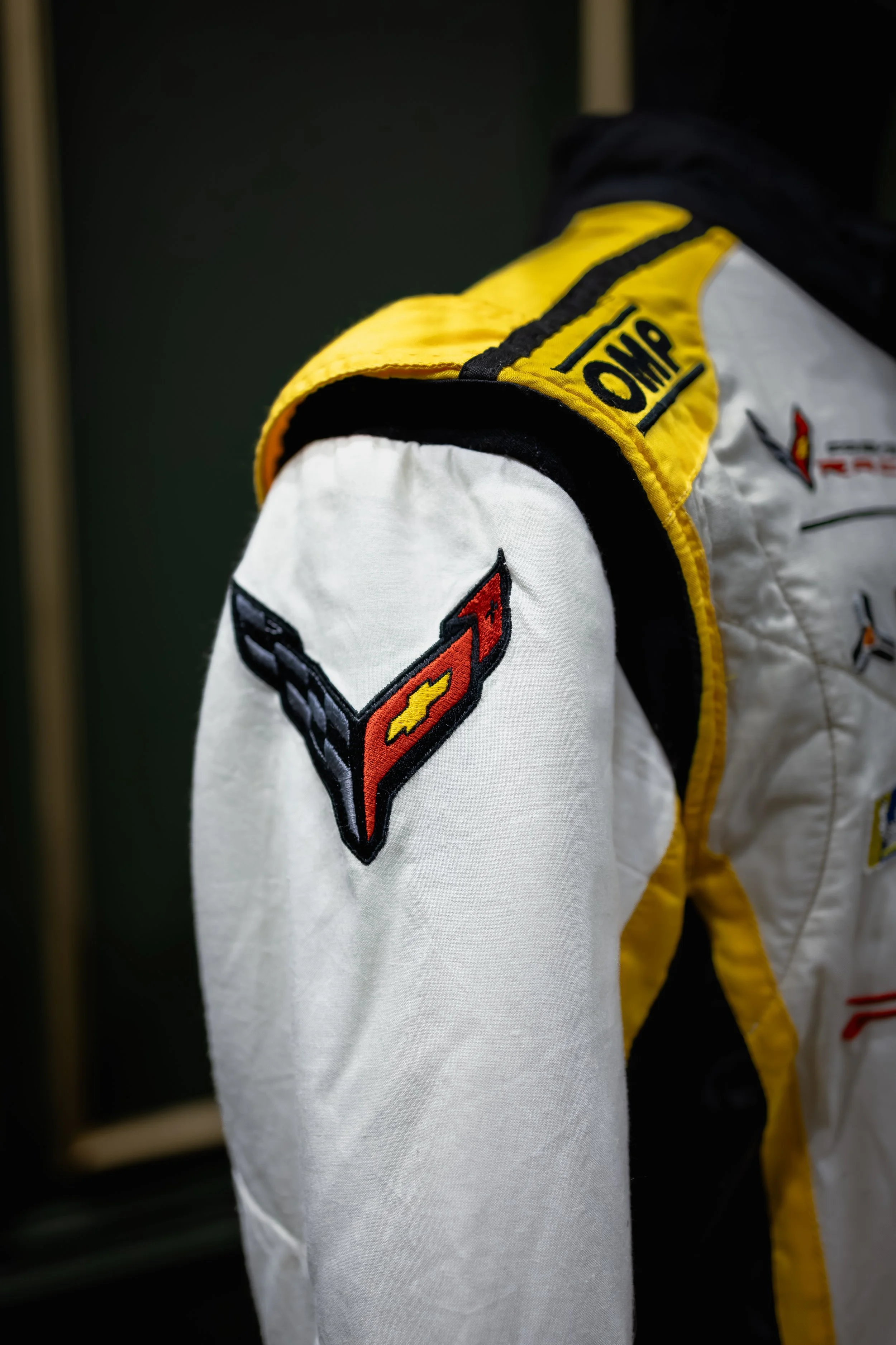 Close-up of a racing suit with a Corvette emblem on the sleeve.