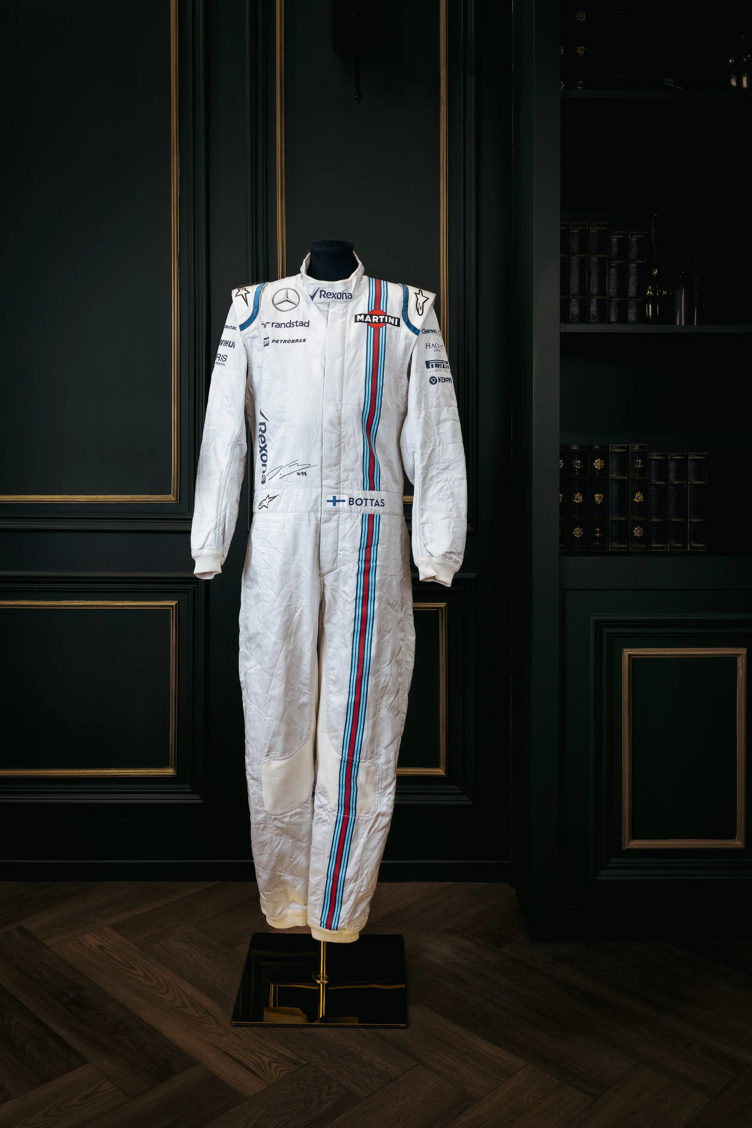 A race car driver celebrating with a bottle of champagne, spraying it in the air, with a British flag in the background.
