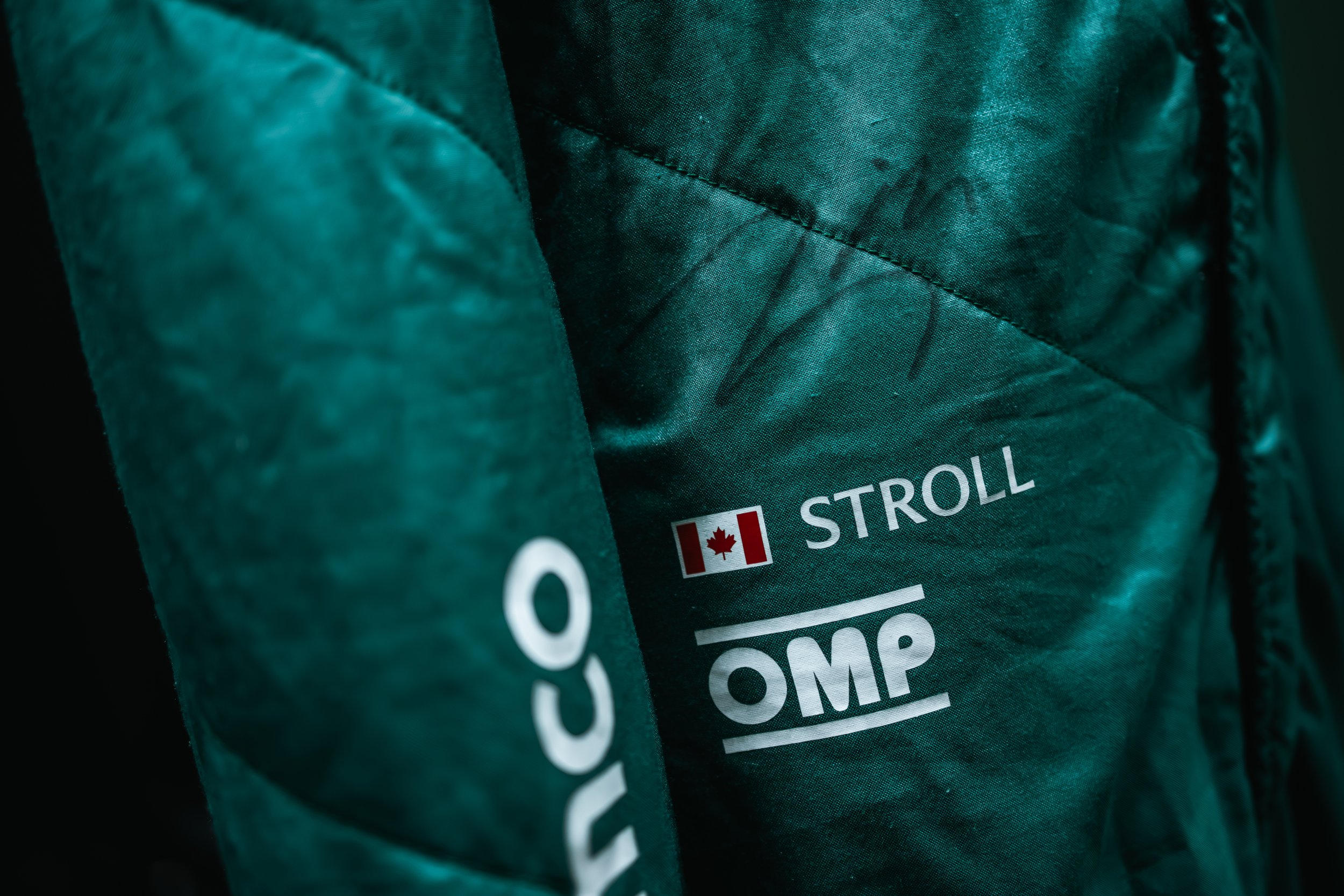 Close-up of a green jacket with the word 'STROLL', a Canadian flag, and the logo 'OMP' printed on it.