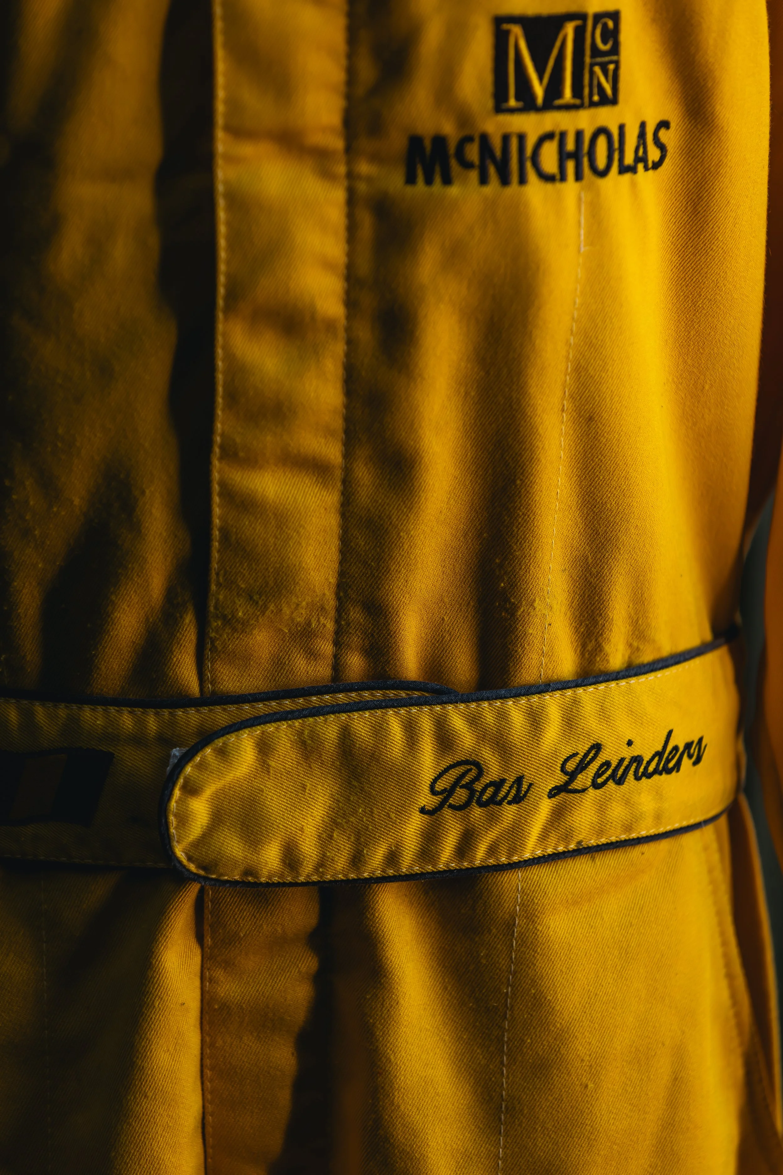 Close-up of a yellow jacket with black embroidery that reads 'Boss Leinders' and a logo with the initials 'MN' at the top.