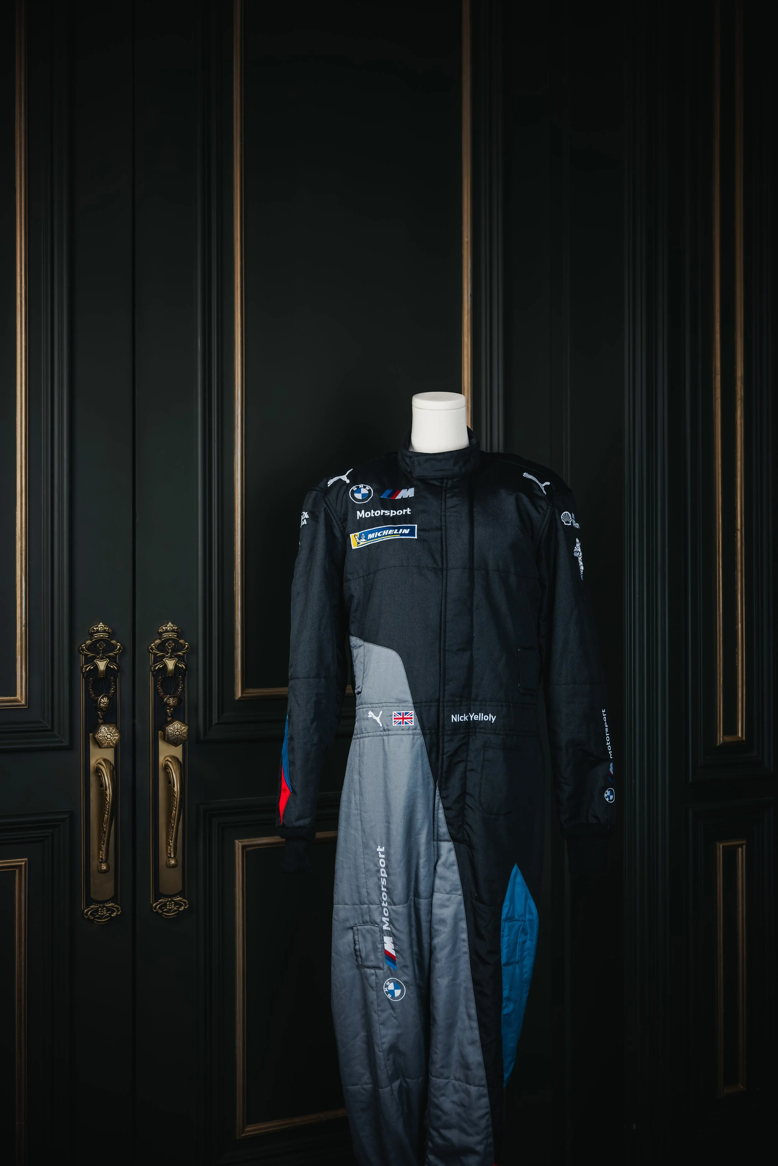 Motorsport racing suit on a mannequin in a dark ornate room door background