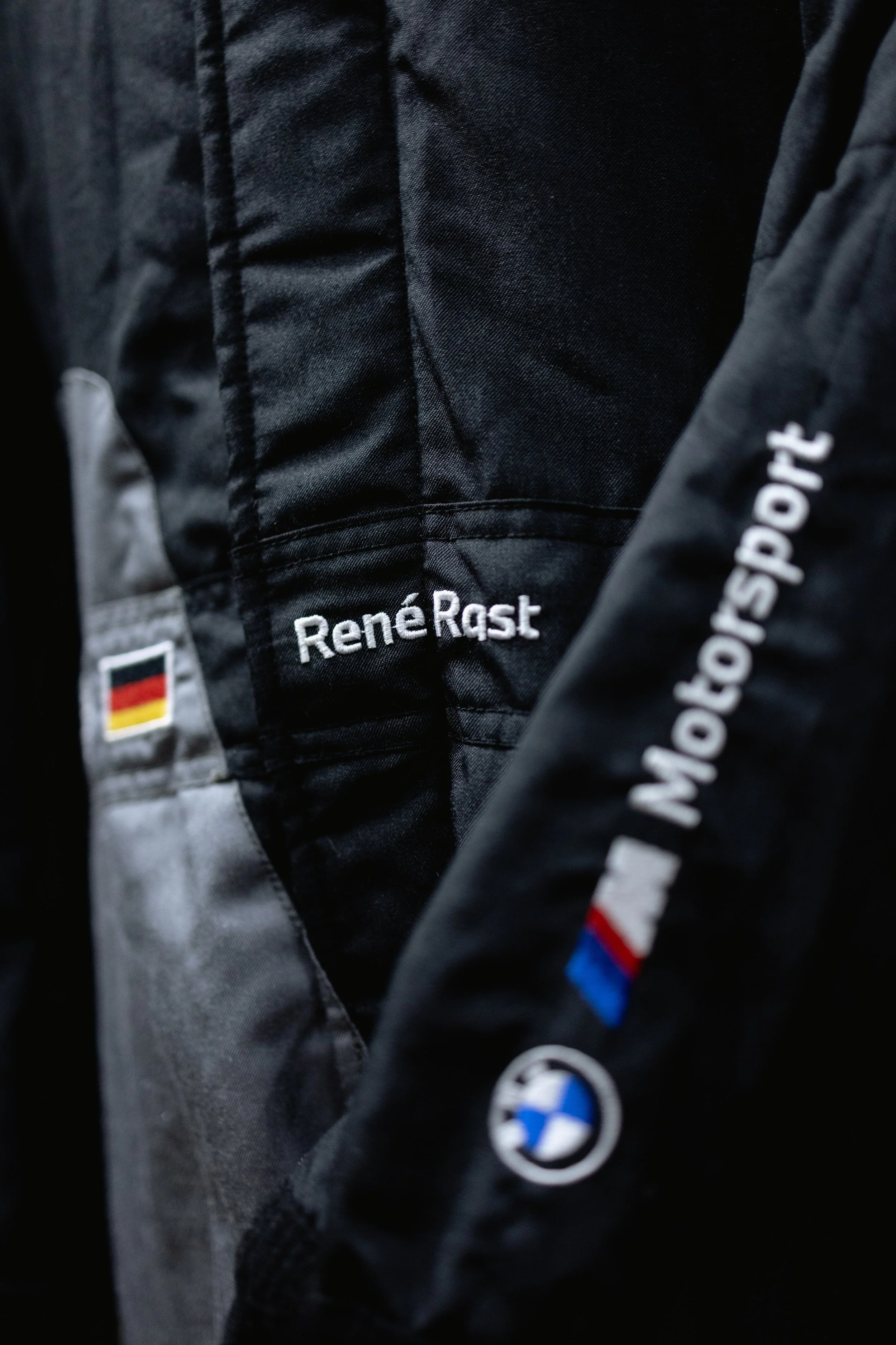 Close-up of black and grey racing jackets with embroidered names, German flag patch, and BMW M logo.