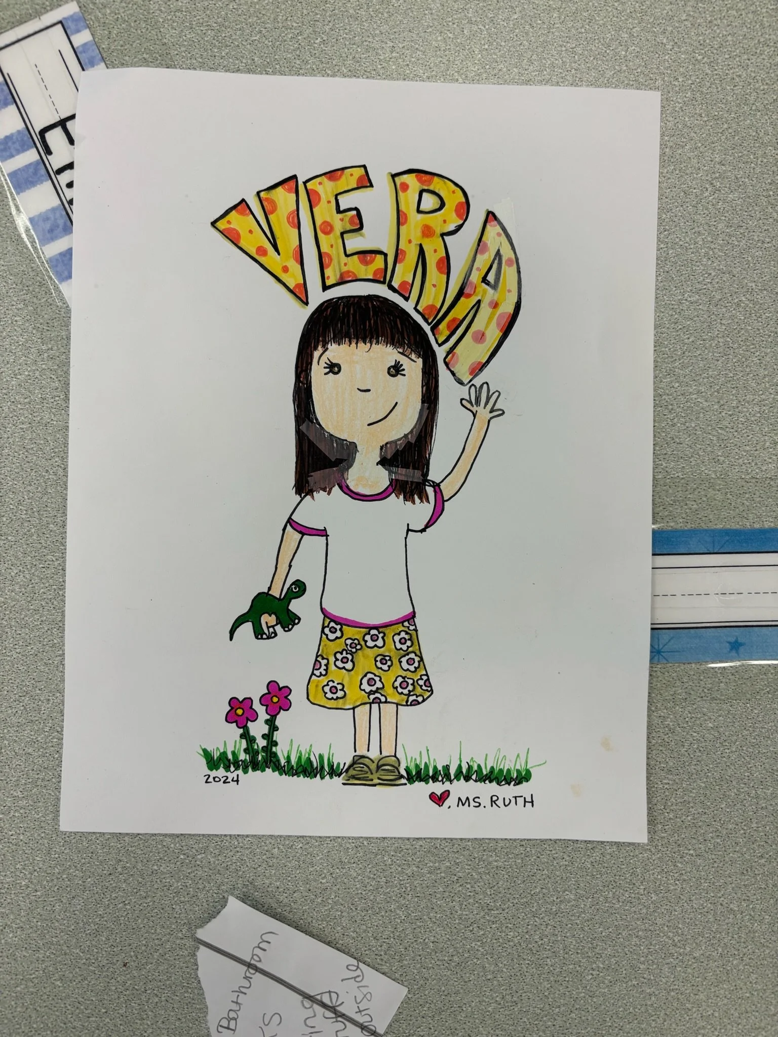 Hand-drawn illustration of a girl with shoulder-length dark hair, wearing a white shirt with pink trim, yellow floral skirt, and sandals. She holds a small green dinosaur toy in her right hand and waves with her left hand. Behind her, the word 'VALER