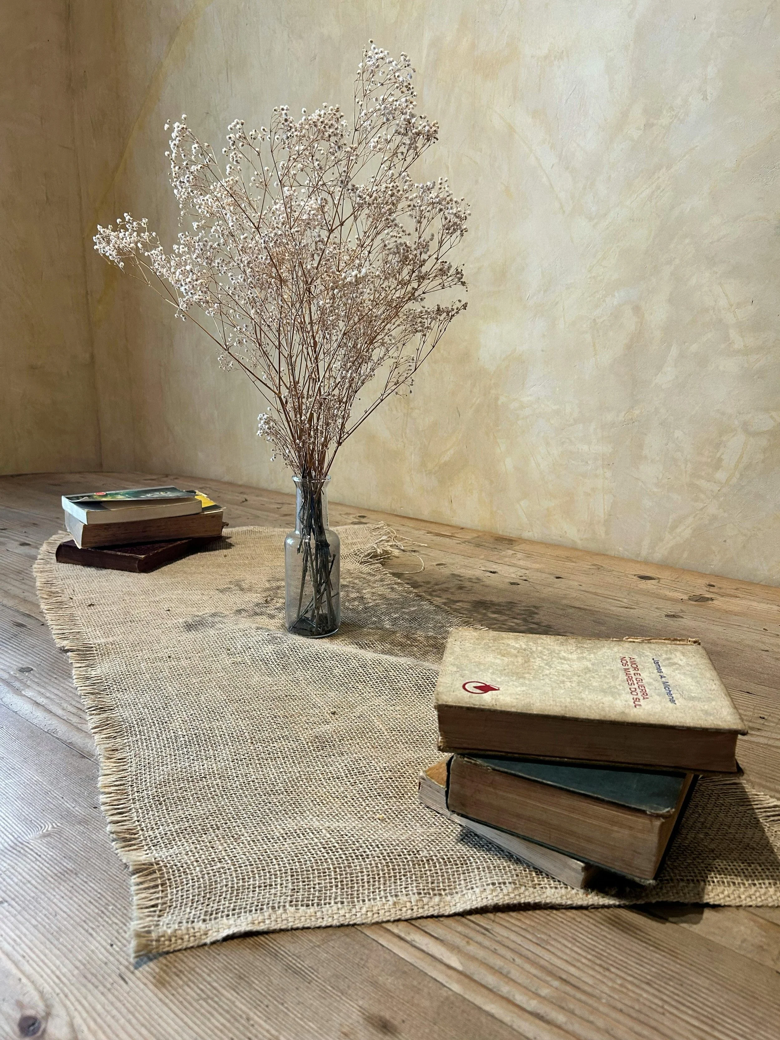 Simple table with books and dried flowers, evoking quiet focus and reflection.
