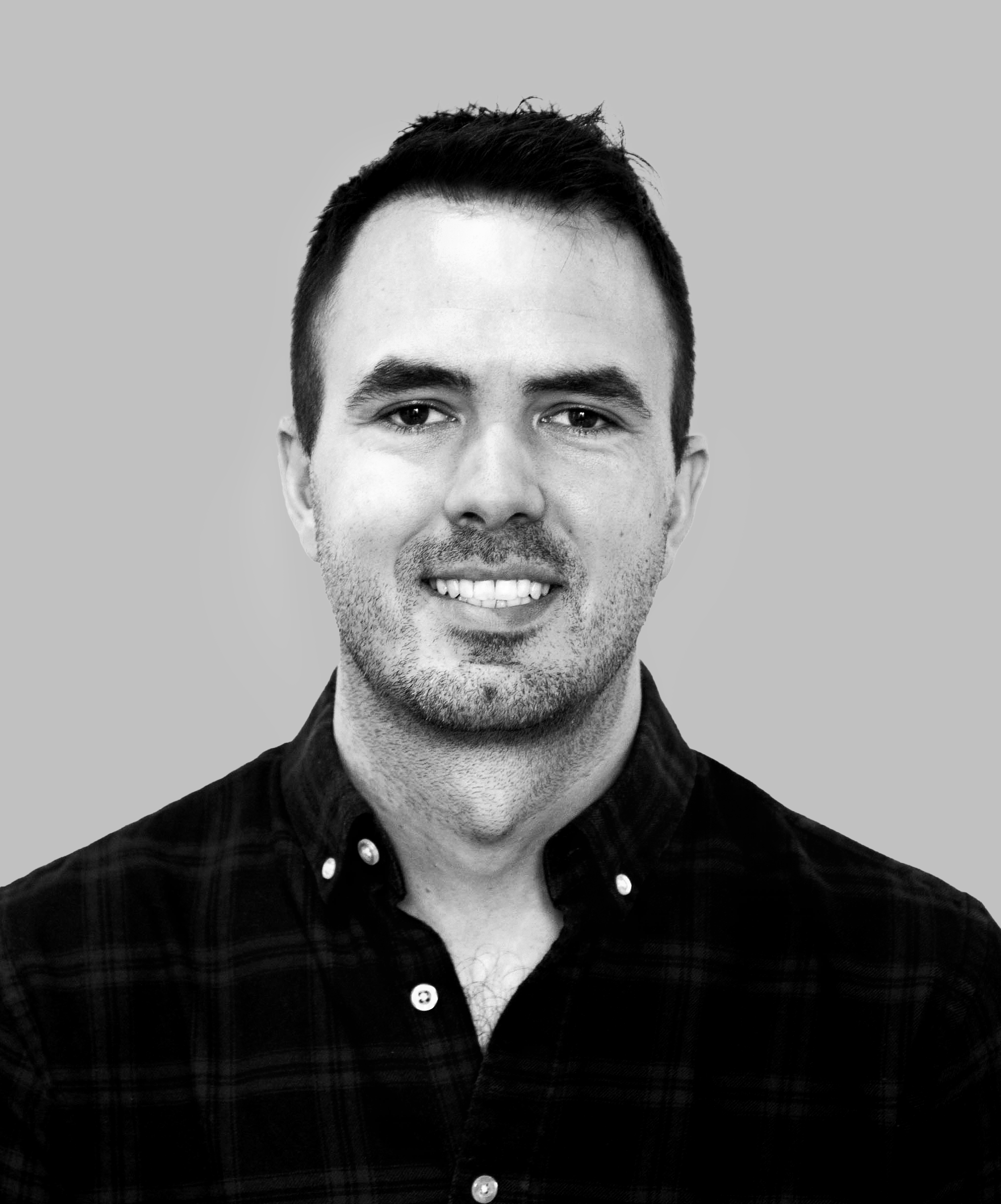 A PORTRAIT PHOTOGRAPH OF KARL CACCHIOLI. HE'S SMILING AND LOOKING AT CAMERA. THE IMAGE IS SHOT IN BLACK AND WHITE.