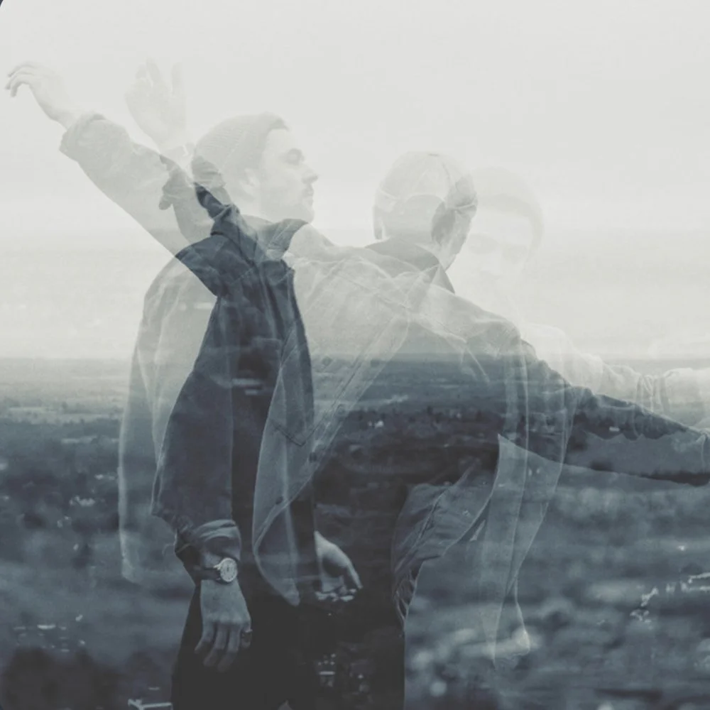 Multiple exposure photograph of a man standing outdoors with his arm raised and looking to the side, blending with a landscape scene.