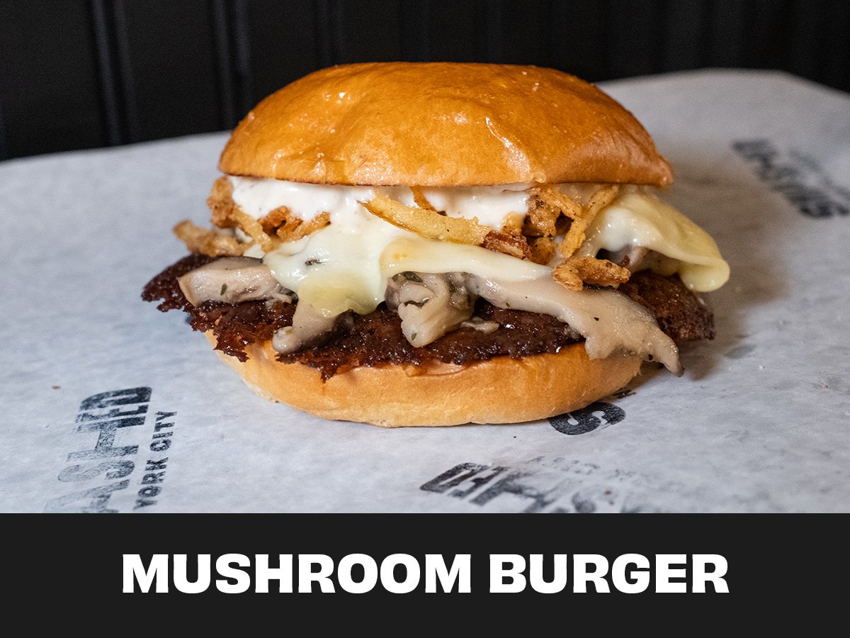 A mushroom burger with a beef patty, melted cheese, grilled onions, crispy fried onion strings, and a toasted bun.