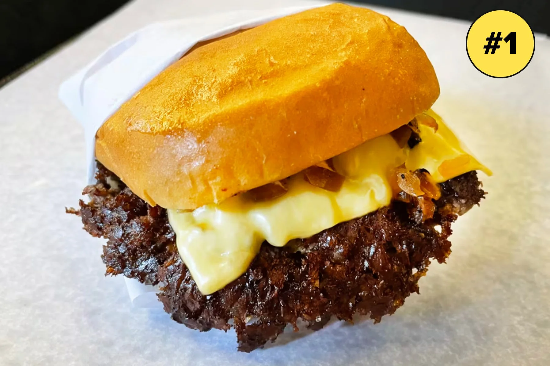 Close-up of a cheeseburger with a beef patty, melted cheese, caramelized onions, and a toasted sandwich bun.