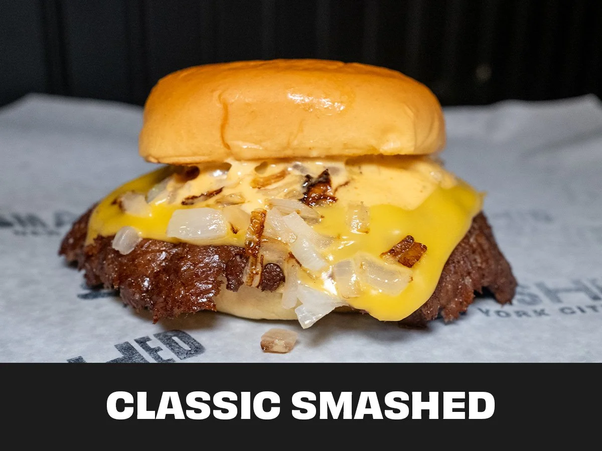 Close-up of a cheeseburger with a beef patty, melted cheese, chopped onions, and a sandwich bun