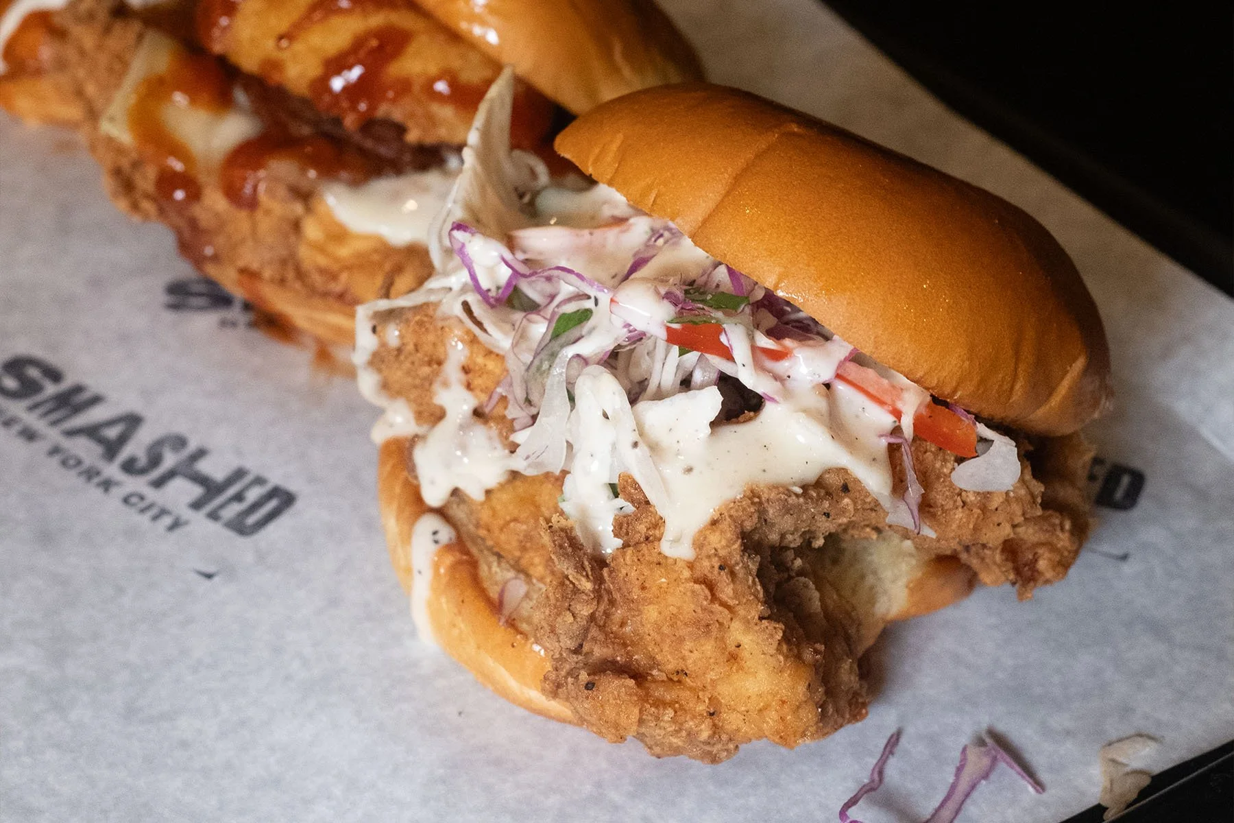 Fried chicken sandwich with coleslaw and a toasted bun.