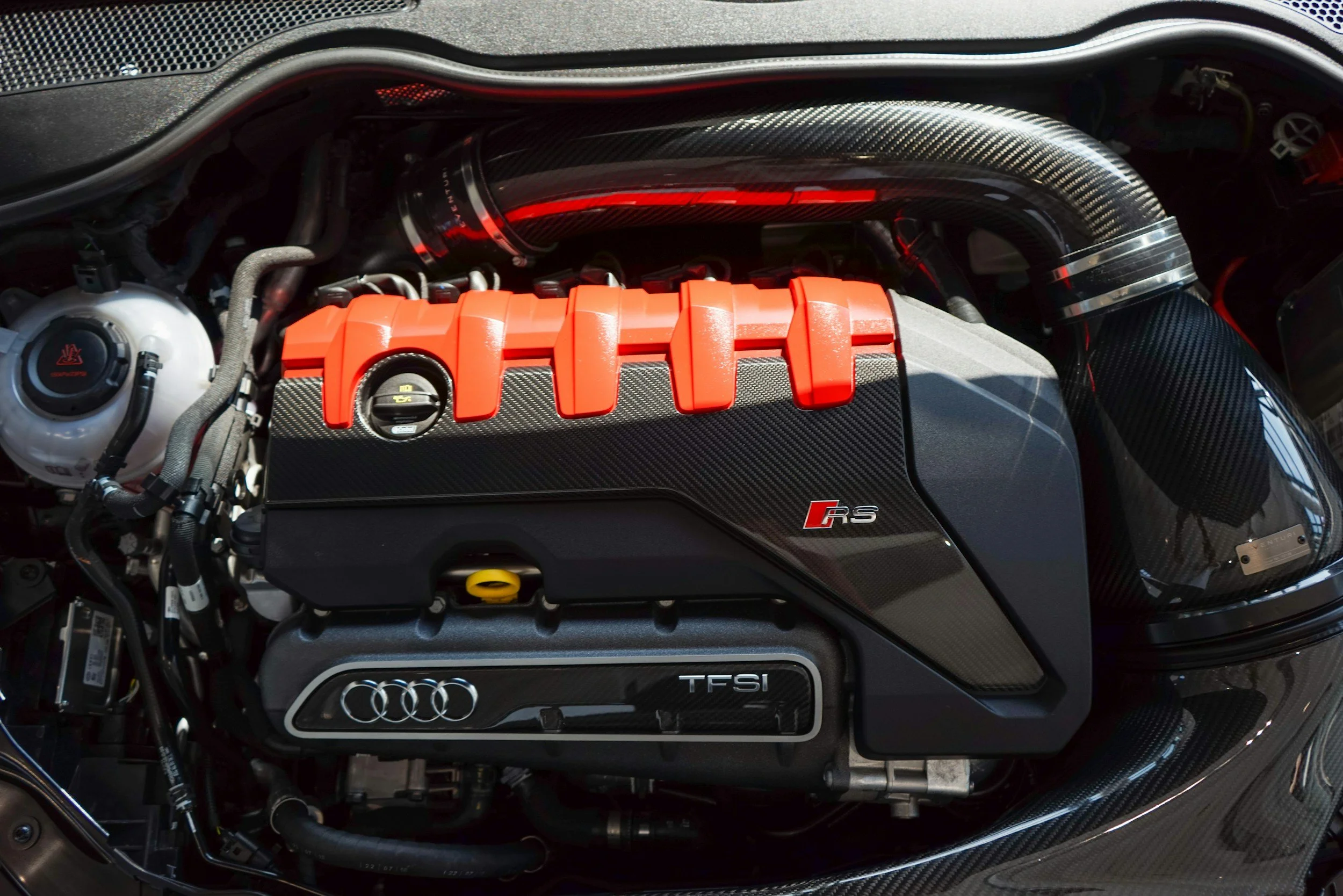 Close-up of a high-performance car engine with red accents and Audi logo.