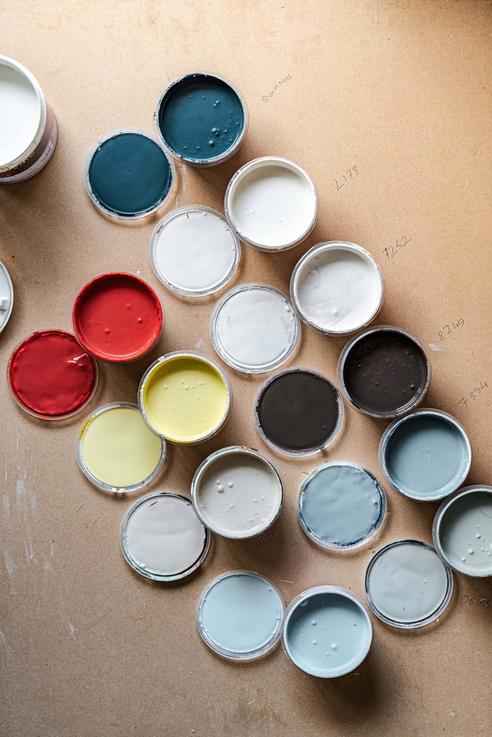 Containers of various colored paint arranged on a tabletop.