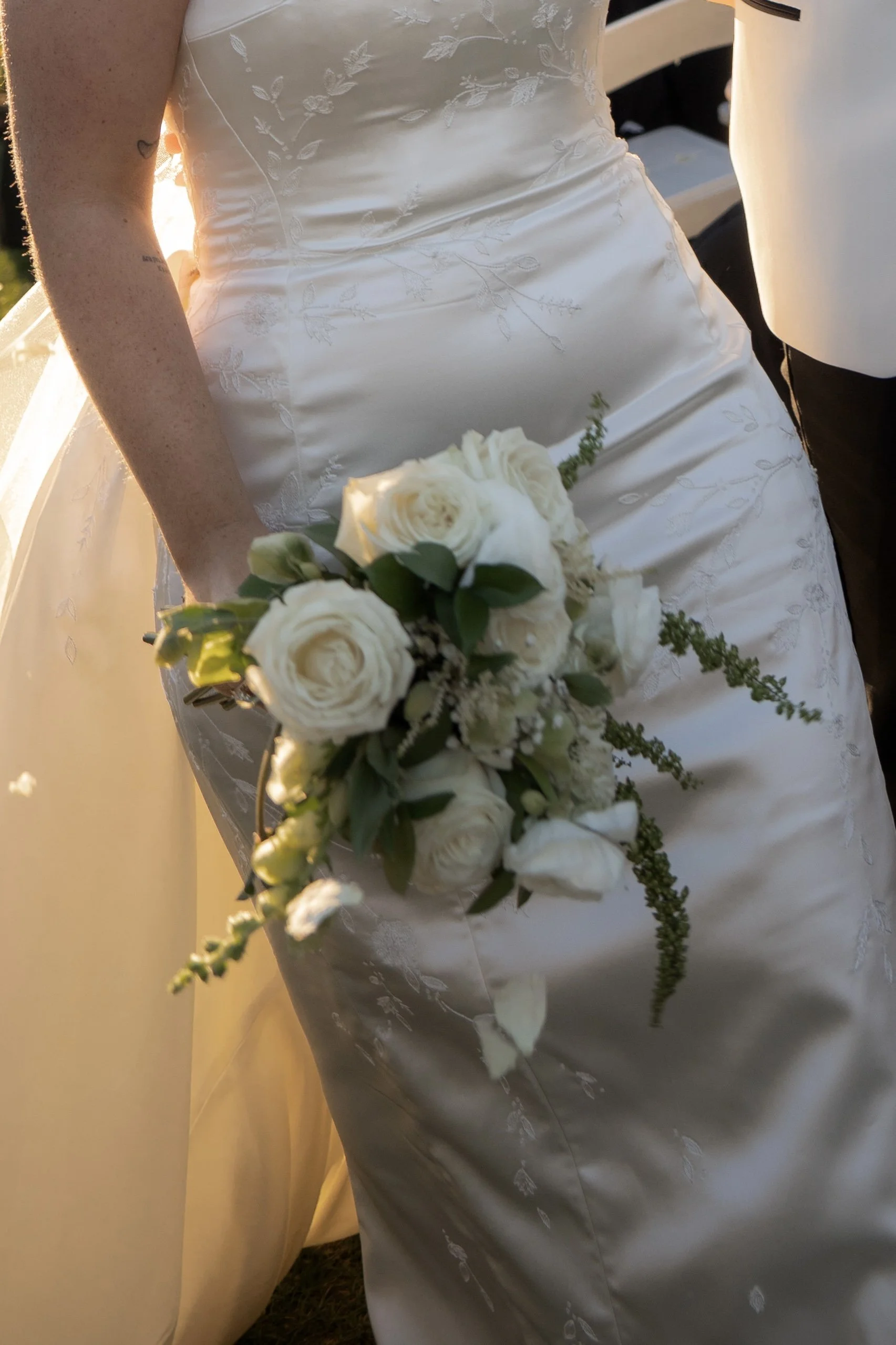 Bride in a white wedding dress holding a bouquet of white roses at her wedding.