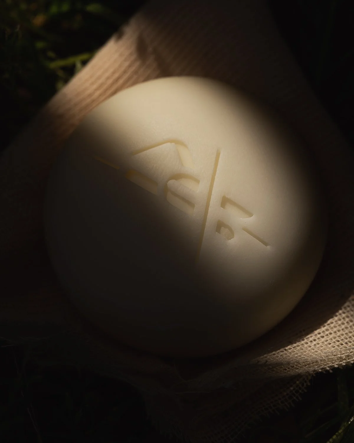 Close-up of a white spherical object with the word 'LOVE' carved into its surface, surrounded by dark shadows and some fabric or mesh material.