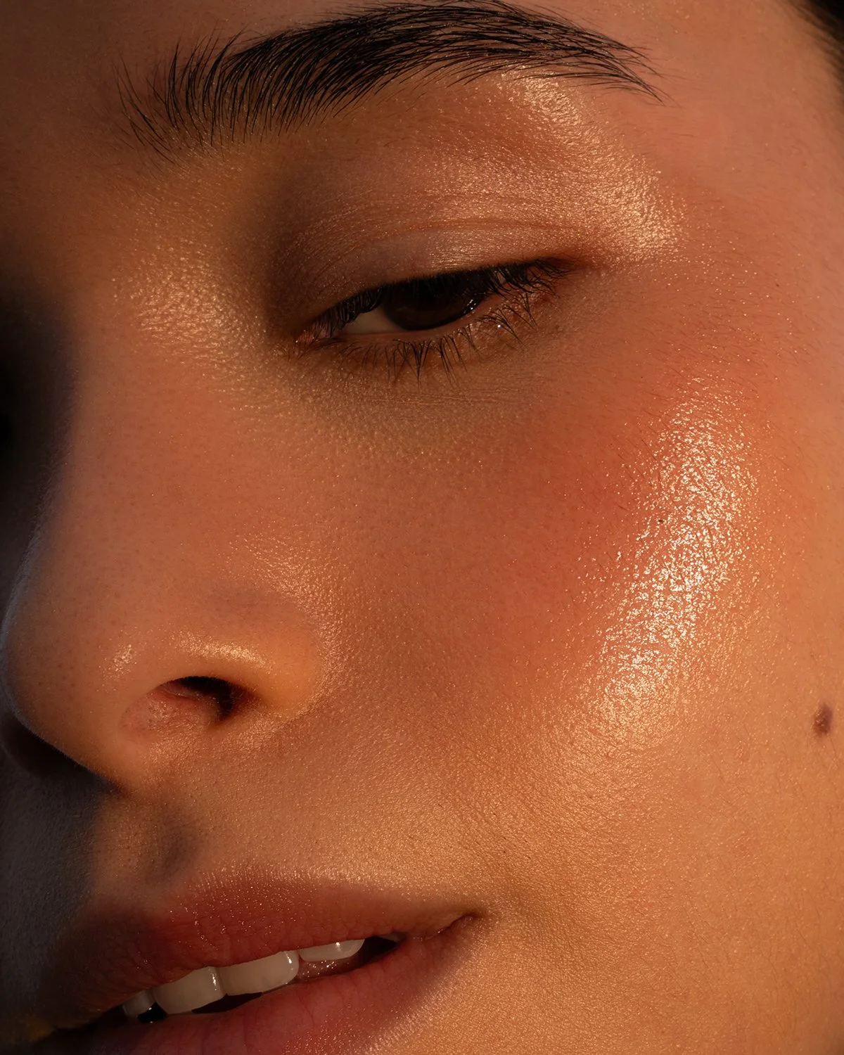 Close-up of a person's face highlighting their eye, nose, and lips with smooth, glowing skin.