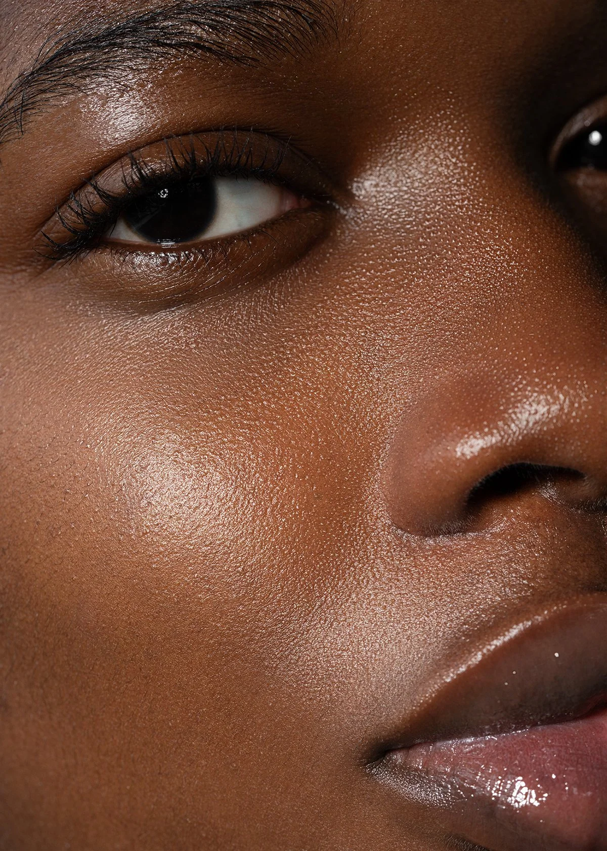 Close-up of a person's face showing their eye, nose, and lips with smooth, glowing skin and detailed facial features.