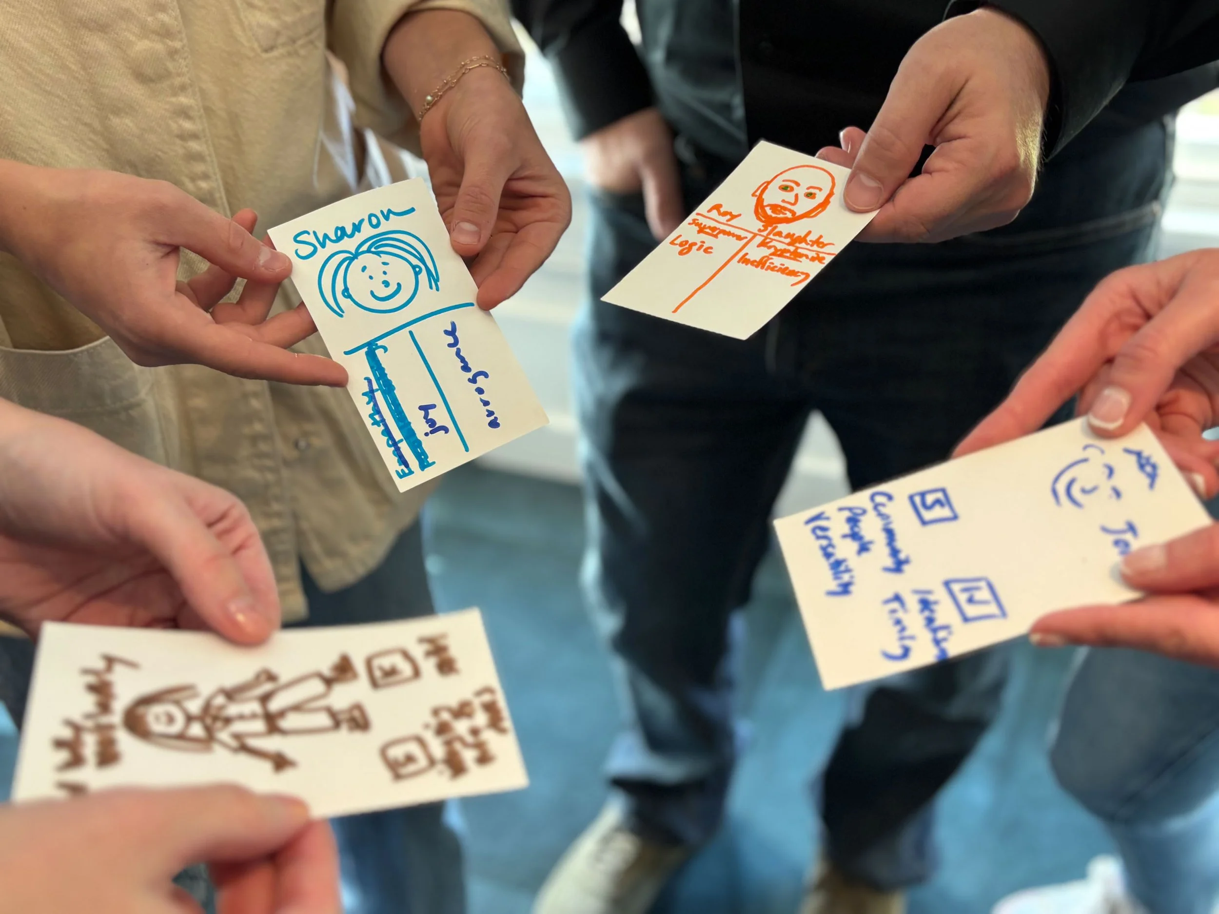 Group of people holding colorful hand-drawn name cards with sketches and text, engaging in a social or team-building activity.
