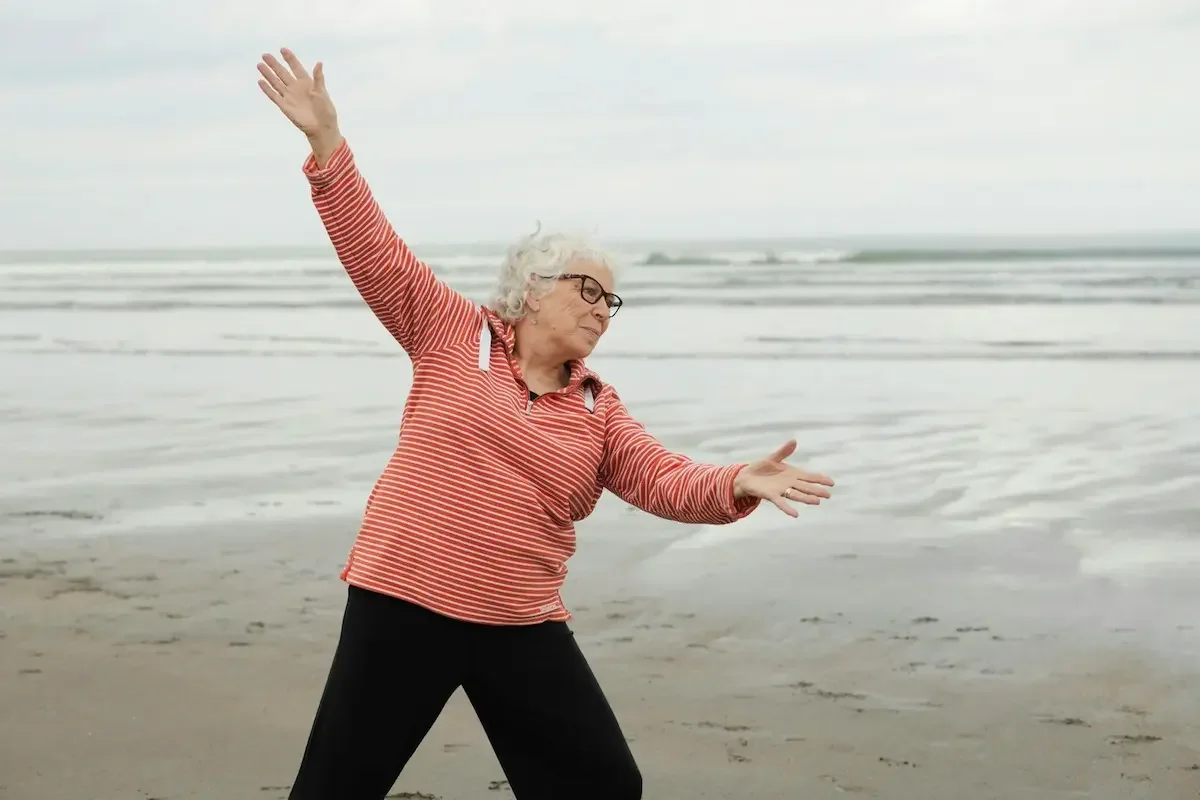 Senior woman enjoying movement and freedom on the beach, creating space for joy and comfort.