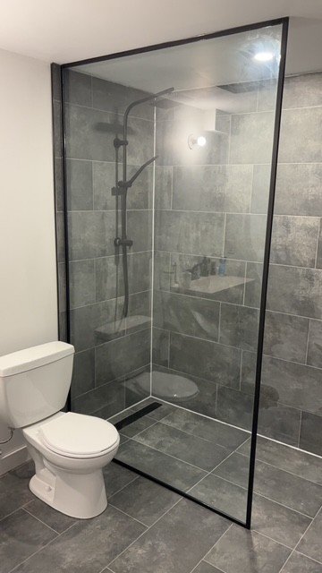 Kitchen with gray cabinets, granite countertops, patterned backsplash, stainless steel refrigerator, stove, and a window above the sink.
