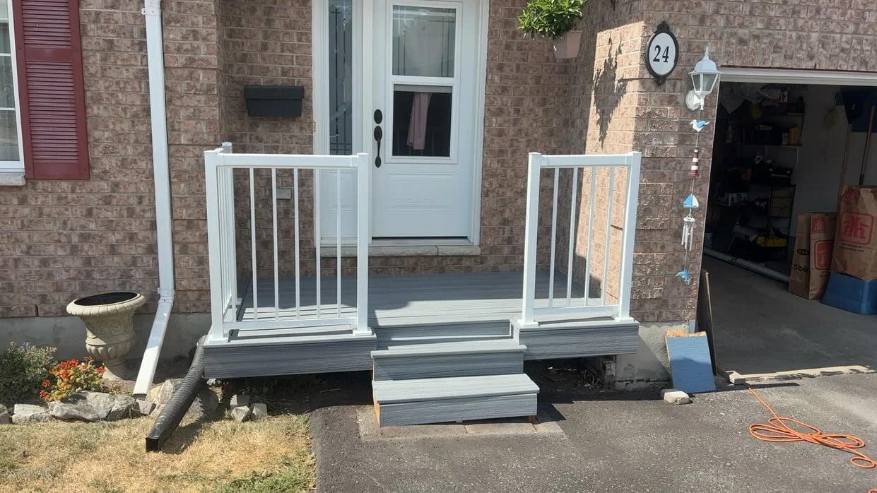 Front porch with white railing, steps, and a door with a window, house number 24, and a garage open showing tools and boxes inside.