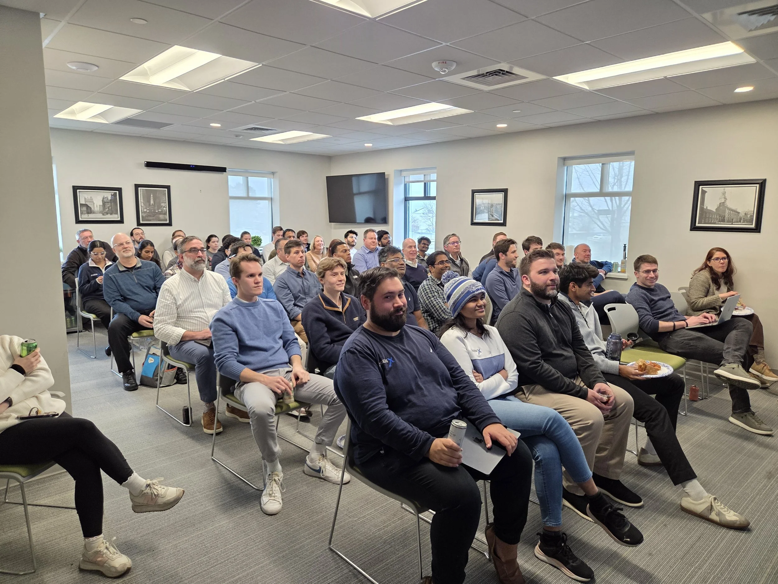 A diverse group of people seated in a conference room, attentively listening to a presentation or speaker.