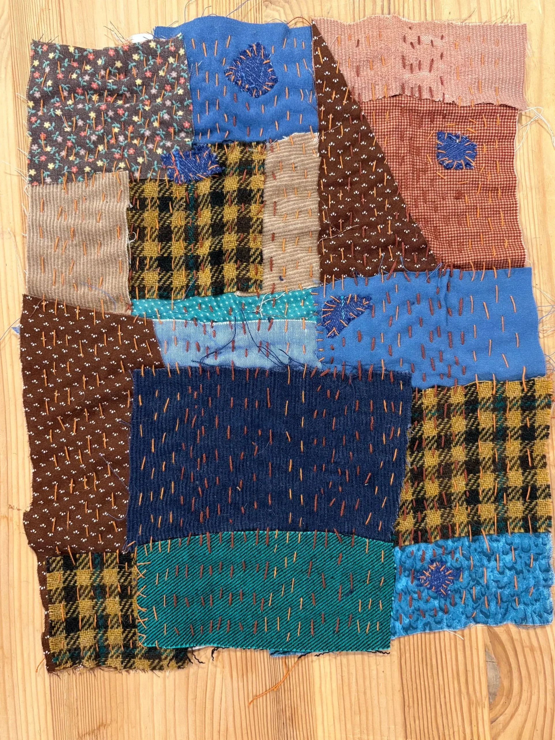 A patchwork quilt with hand stitching running vertically through the multicolored fabrics
