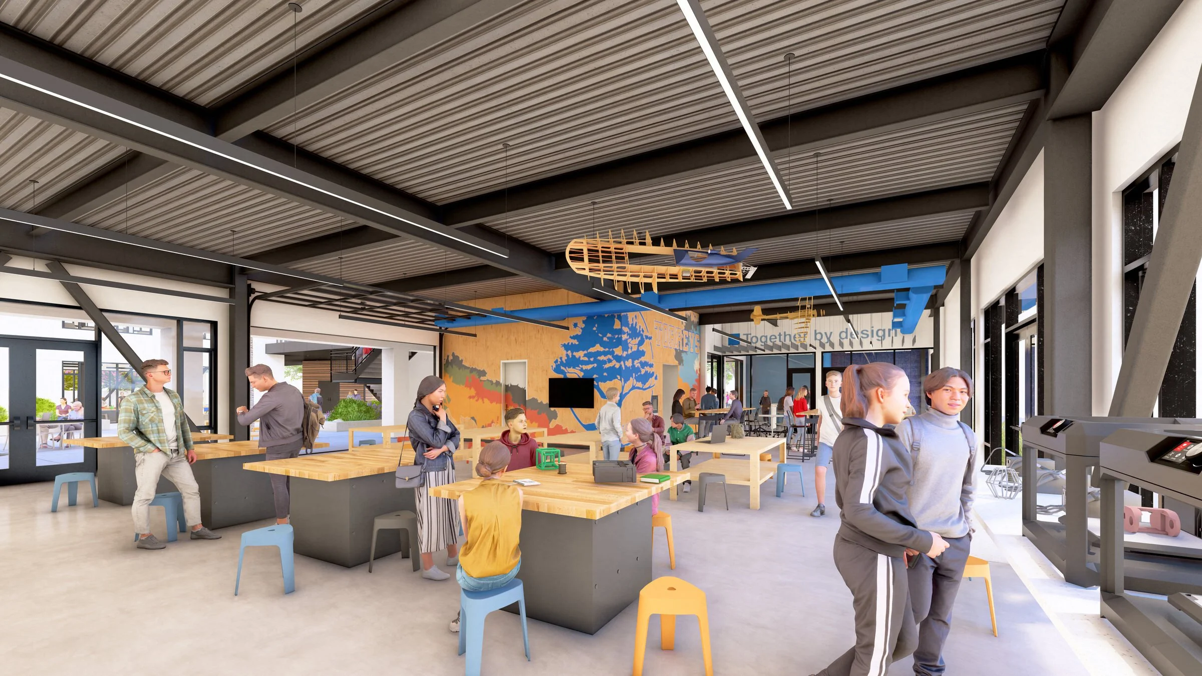 Modern classroom or workshop with students interacting, wooden tables, colorful stools, wall murals, and decorative airplane skeleton. Large windows provide natural light.