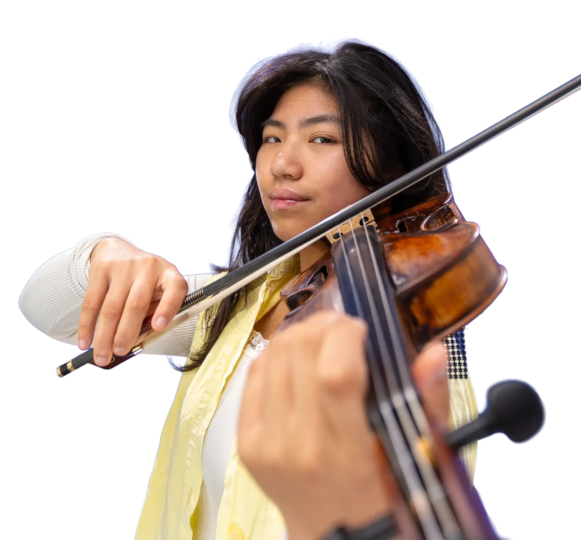 Young woman playing violin, looking at camera, wearing a yellow top, with dark hair, against a plain white background.