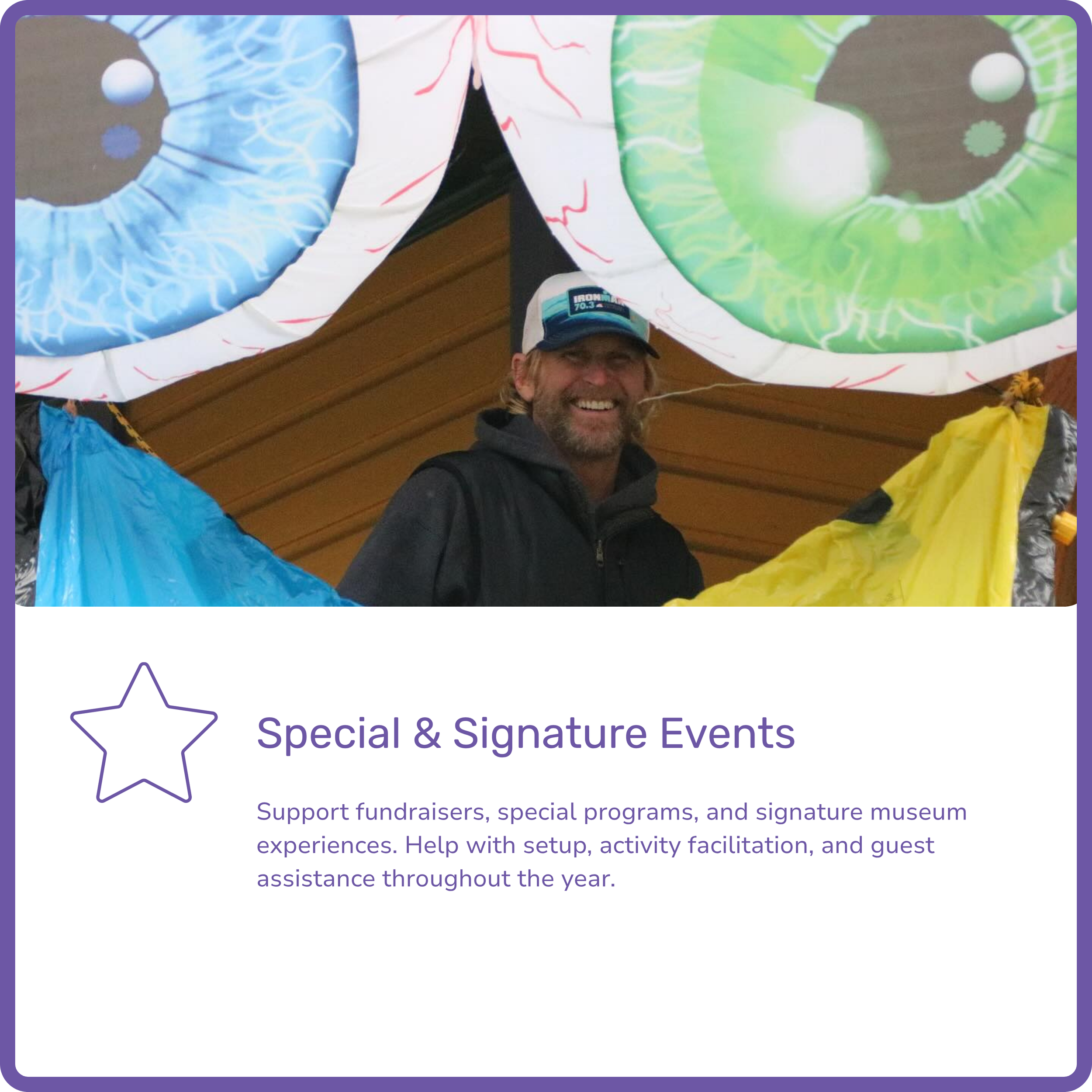 A smiling man wearing a baseball cap and black jacket, standing beneath large inflatable rings with designs resembling eyeballs, inside a wooden structure, with purple border and text about special events below.