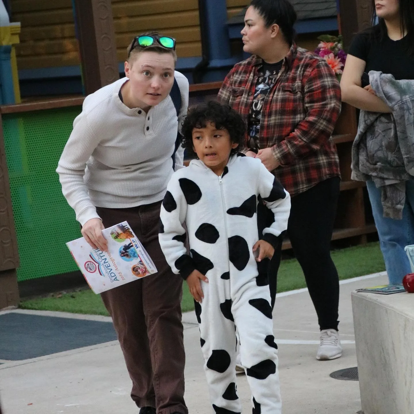 A guest in a cow-print onesie walks with a chaperone during an evening Storybook Adventure rental.
