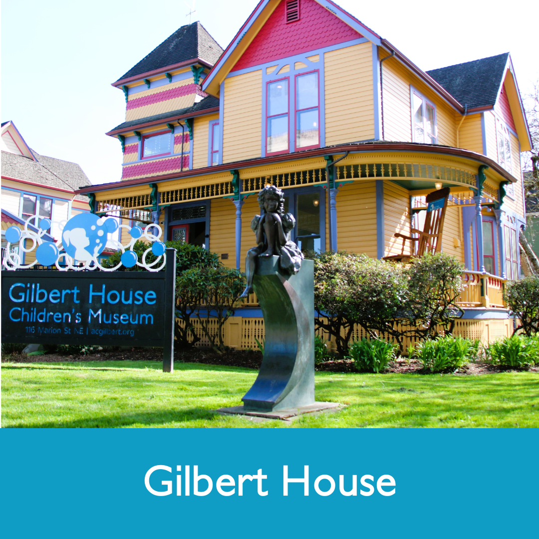 Colorful, Victorian-style house with a sign reading "Gilbert House Children's Museum" in front and a sculpture of a child sitting on a curved pedestal in the yard.