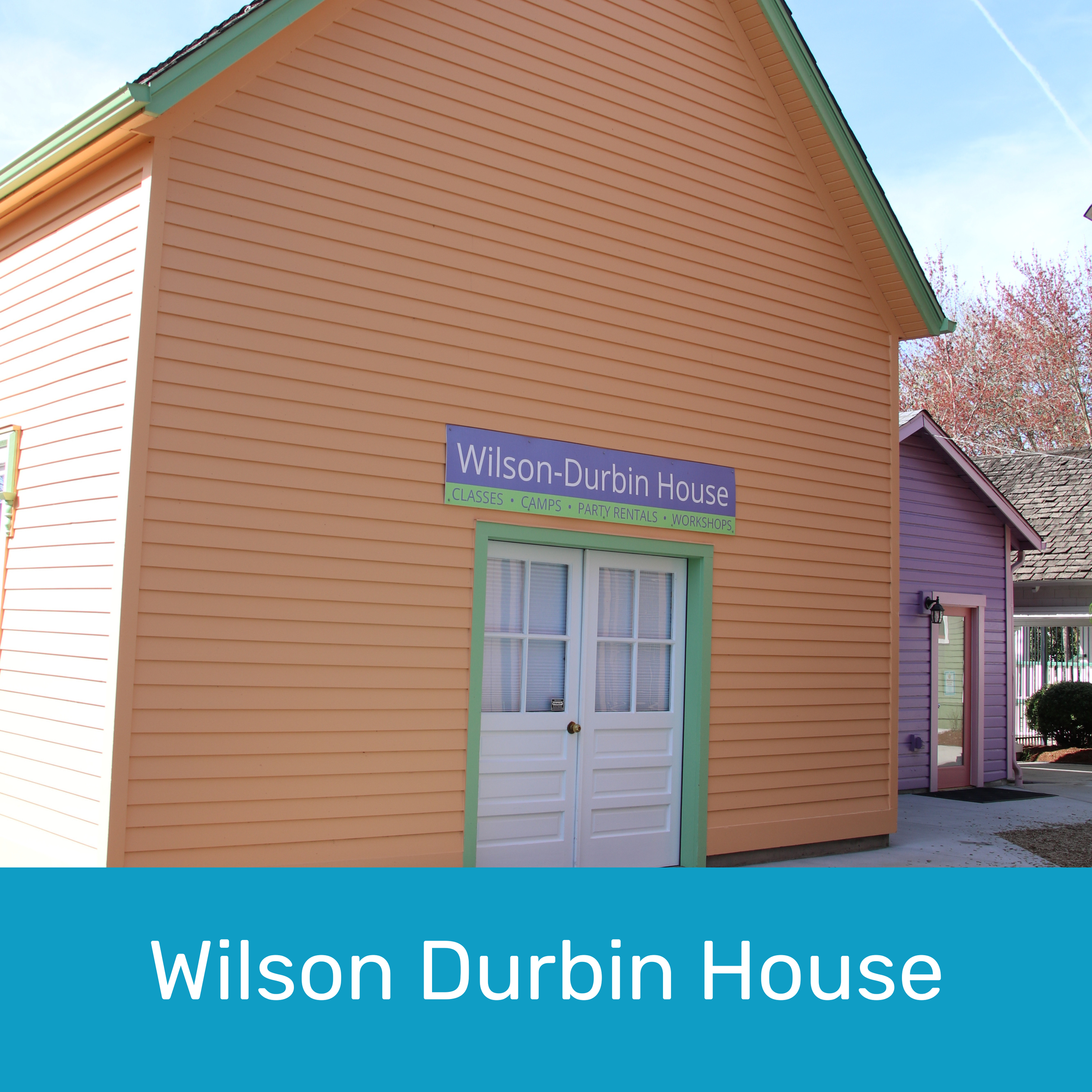 Colorful building with pastel orange exterior, green trim around door, and a purple sign that reads "Wilson-Durbin House" with additional details about classes, camps, party rentals, and workshops.