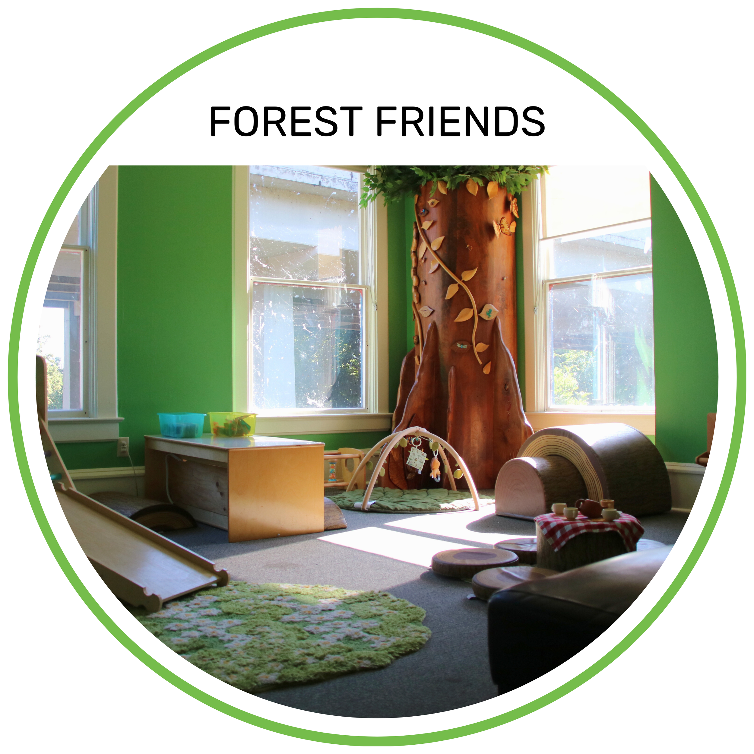 Indoor playroom with green walls, a large artificial tree, and natural light from windows. Contains toys, a slide, and a small table.