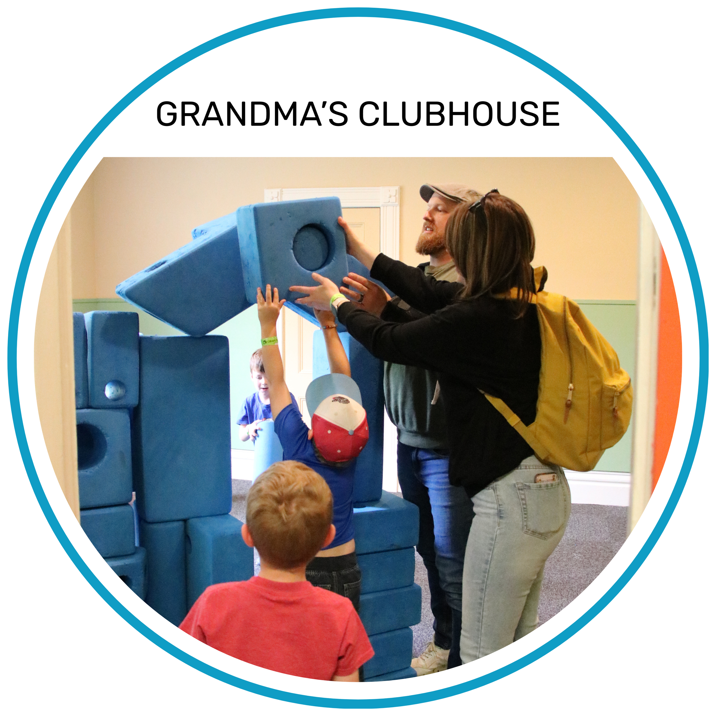 Adult and child working together to build a structure using large, blue foam blocks in the exhibit area.