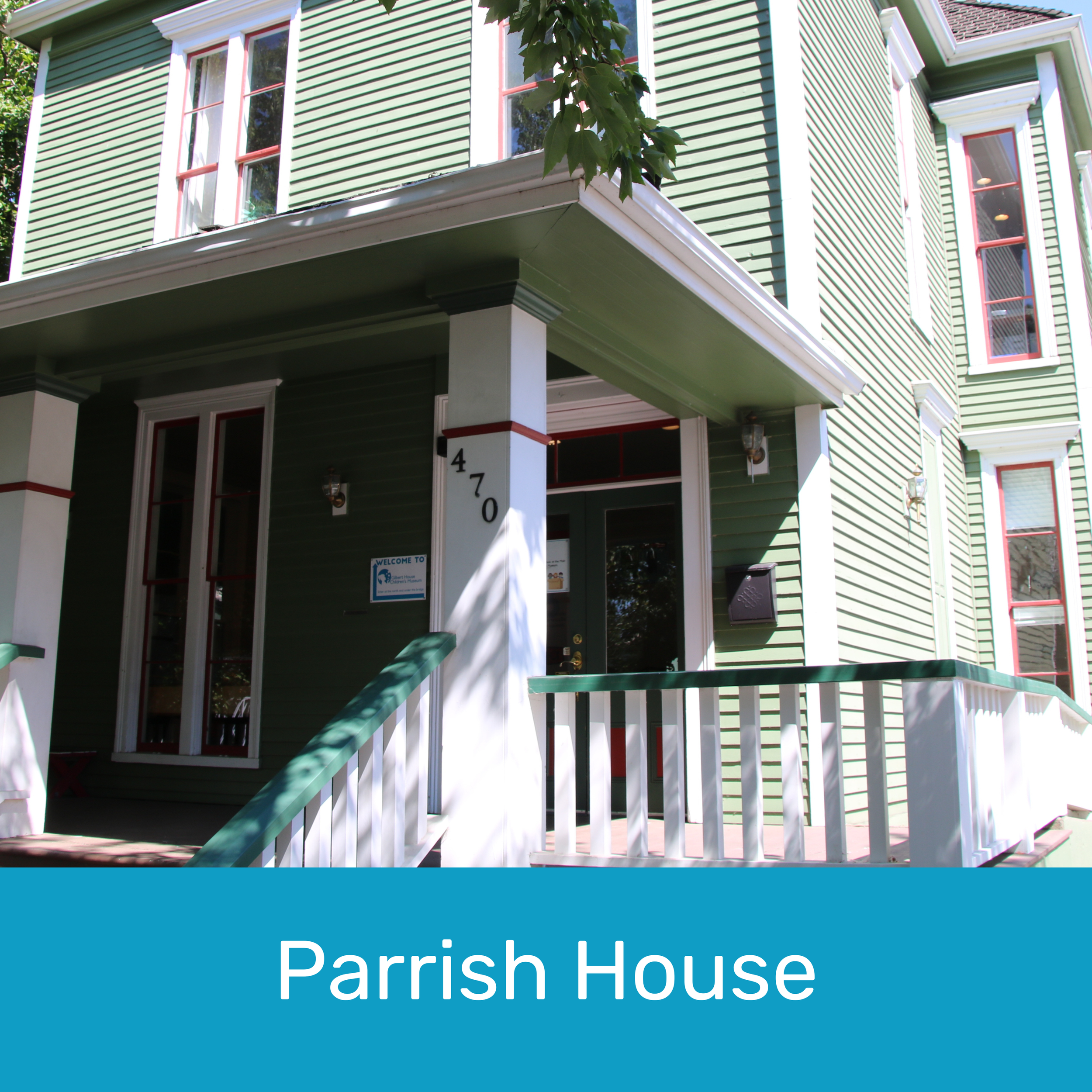 A green two-story house with white trim and a porch, featuring a front door, several tall windows, and a small sign on the porch that says "Welcome to". The house number 470 is visible on a white pillar of the porch, and there is a mailbox next to the door.