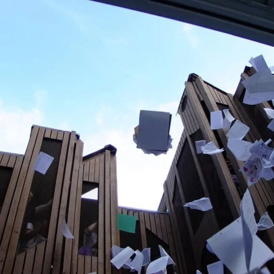 Graduates celebrate by tossing papers in the air during an evening party in the Outdoor Discovery Area.