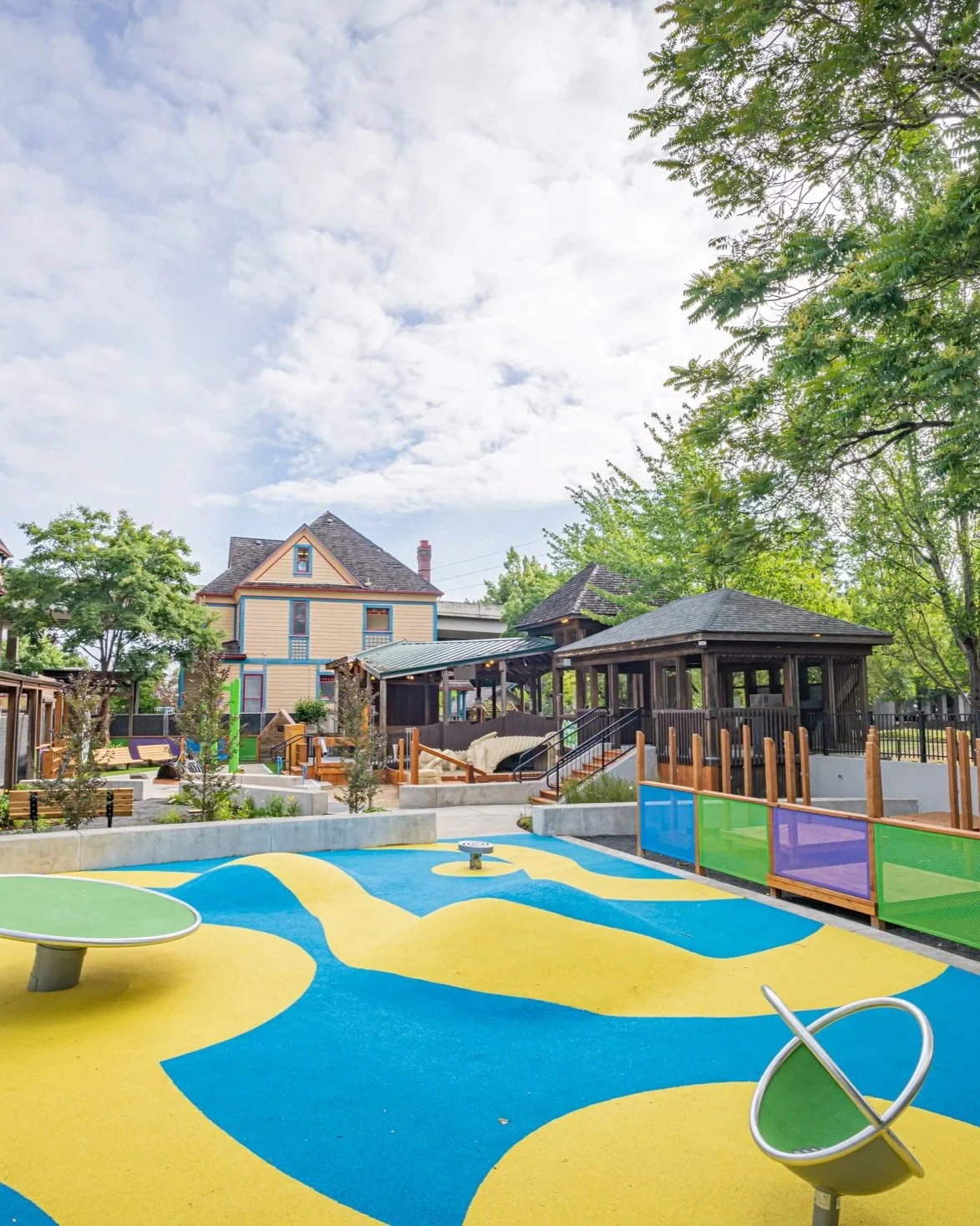Colorful aerial view of the museum's outdoor 20,000-square-foot Discovery Area with blue, yellow, and green patterned rubber surfacing and structures for children's active play.