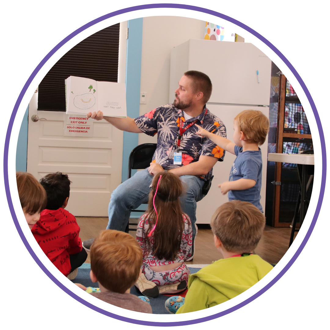 A man reading a children's book to a group of kids in a classroom or daycare setting.