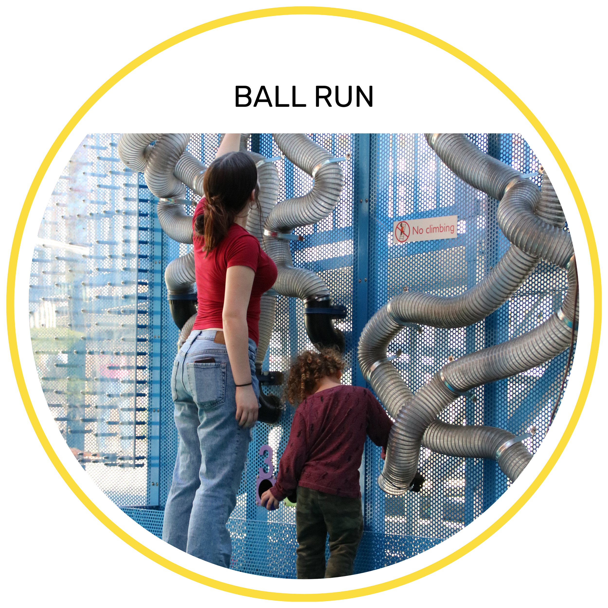 Two children, one girl and one boy, playing on a metal tube maze at a playground, with a sign that says 'No climbing' in the background.