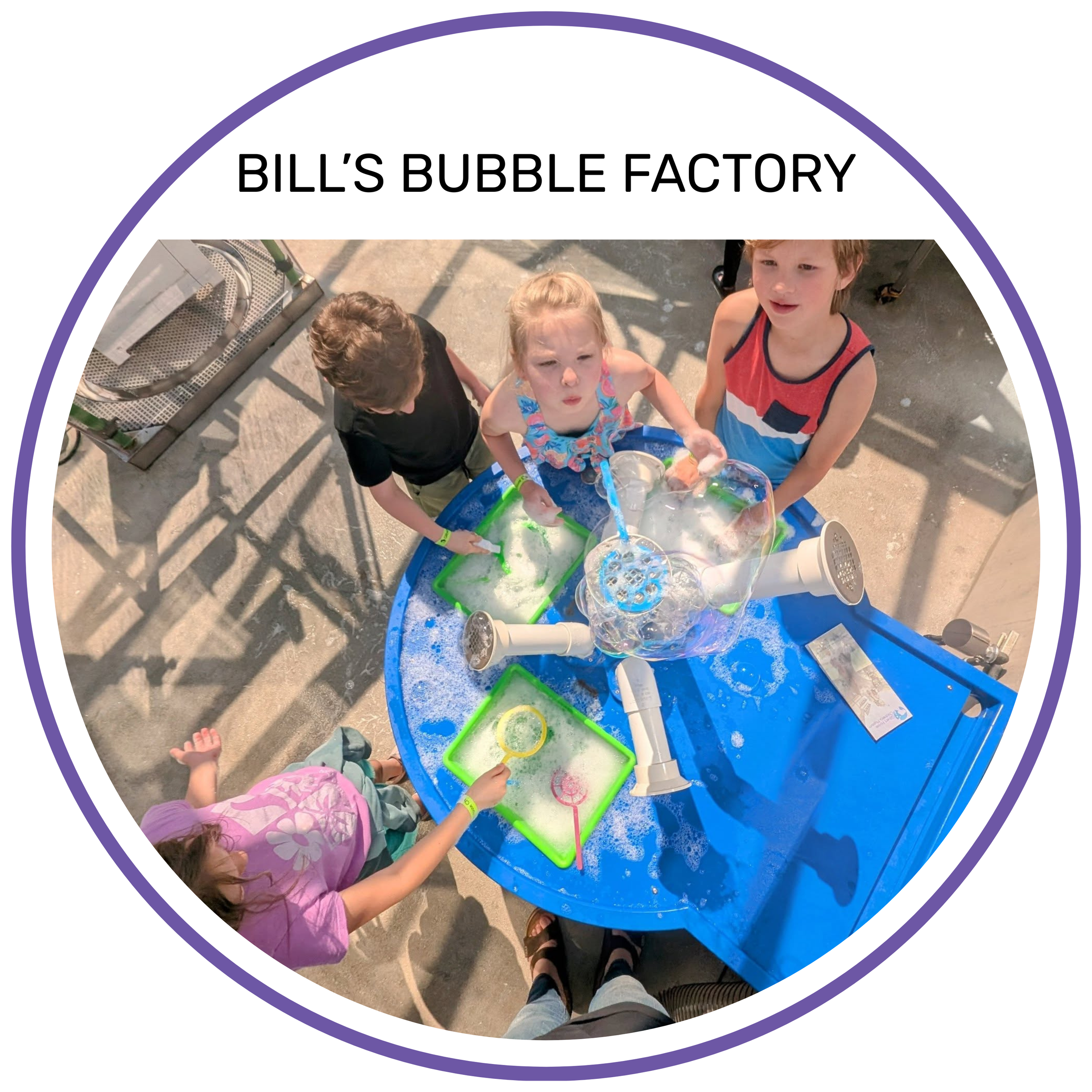 Children at Bill's Bubble Factory playing with soap and bubbles at a blue table.