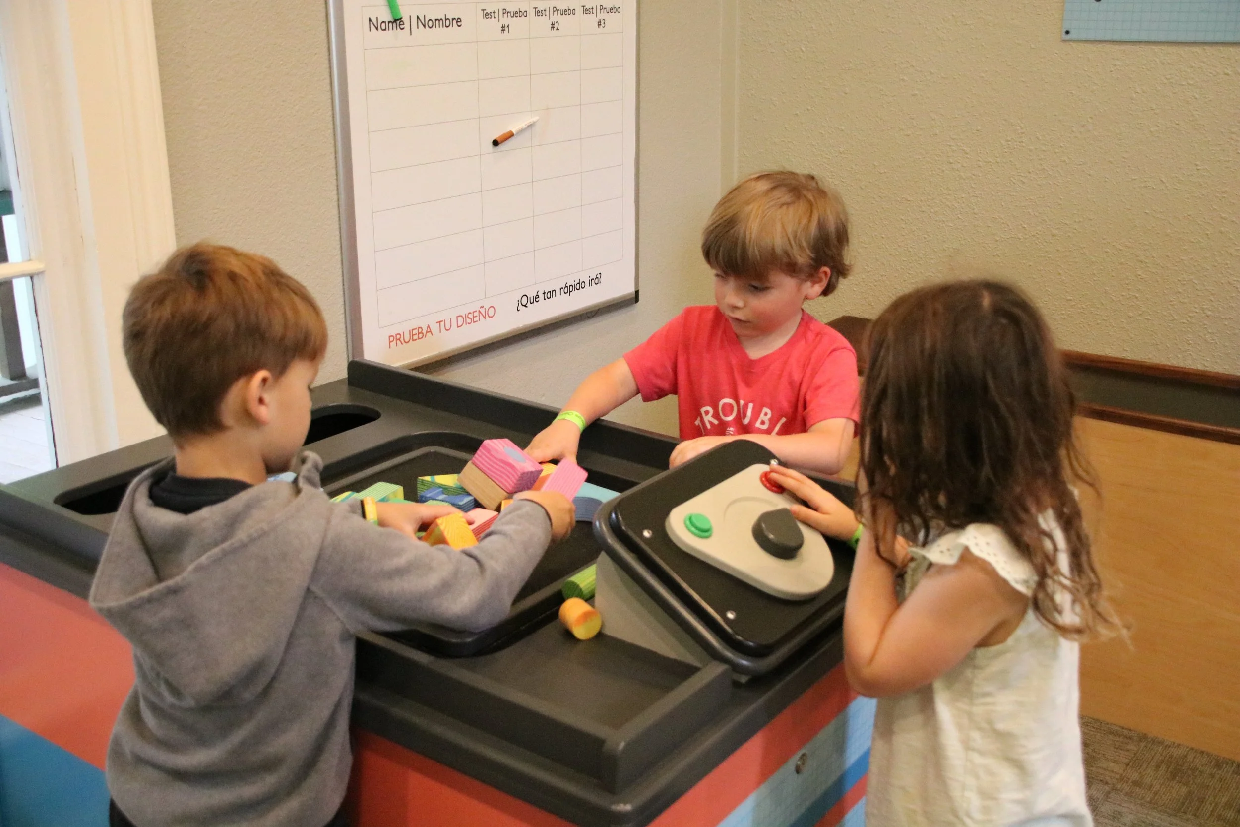 Three children playing with toys at an indoor play area.