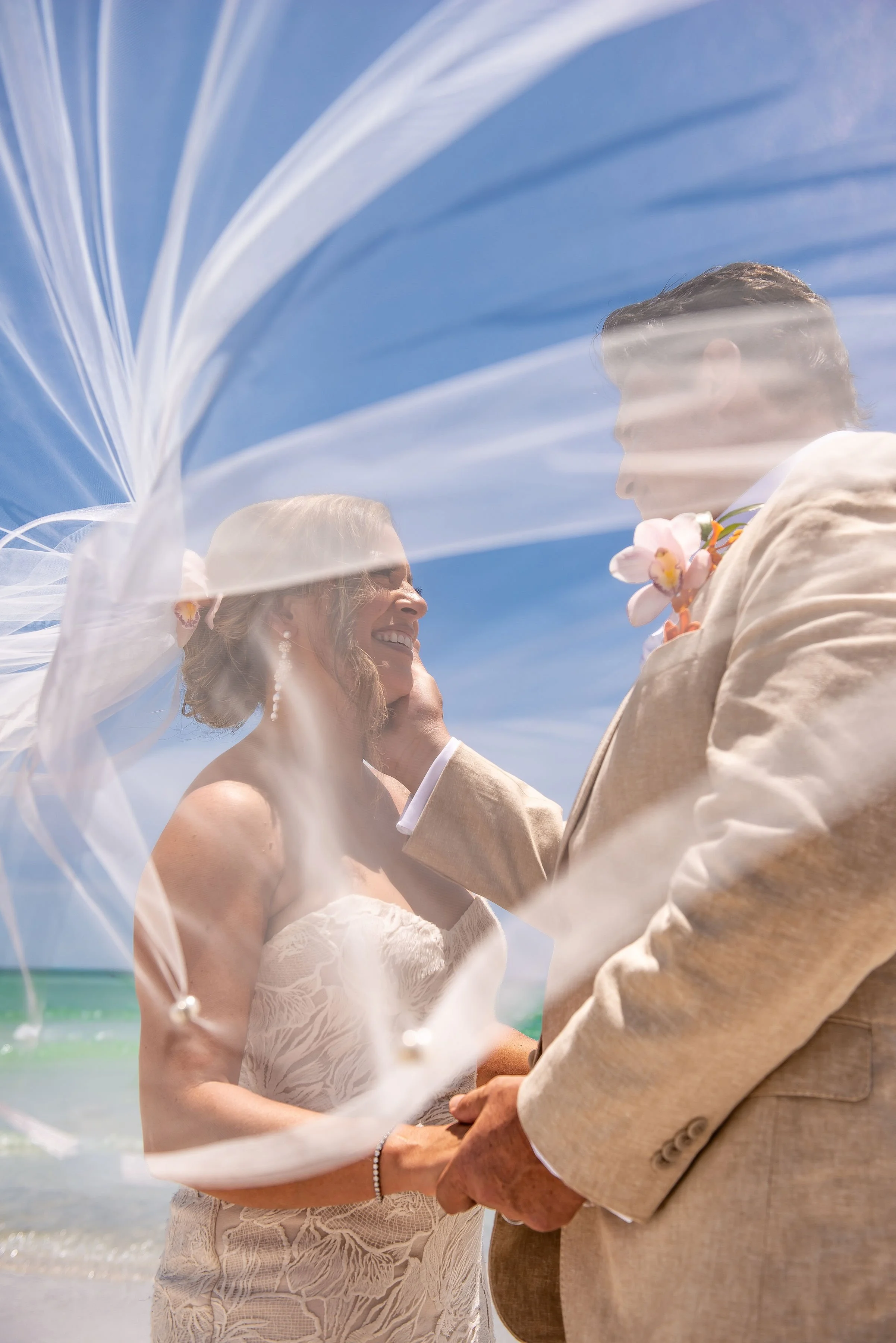 Bride and Groom smiling at each other with wedding veil