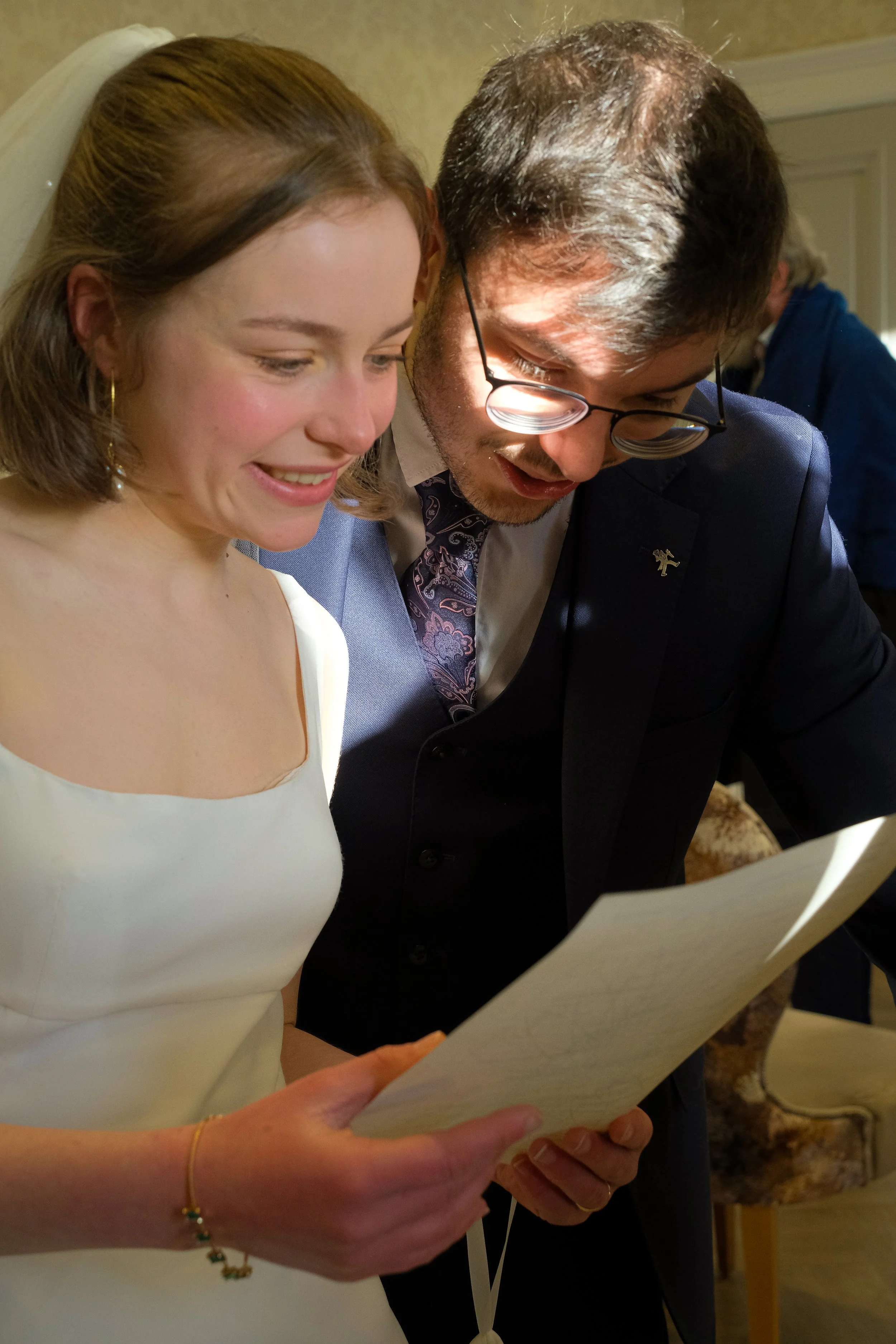 A bride and groom looking at a document together during their wedding celebration.